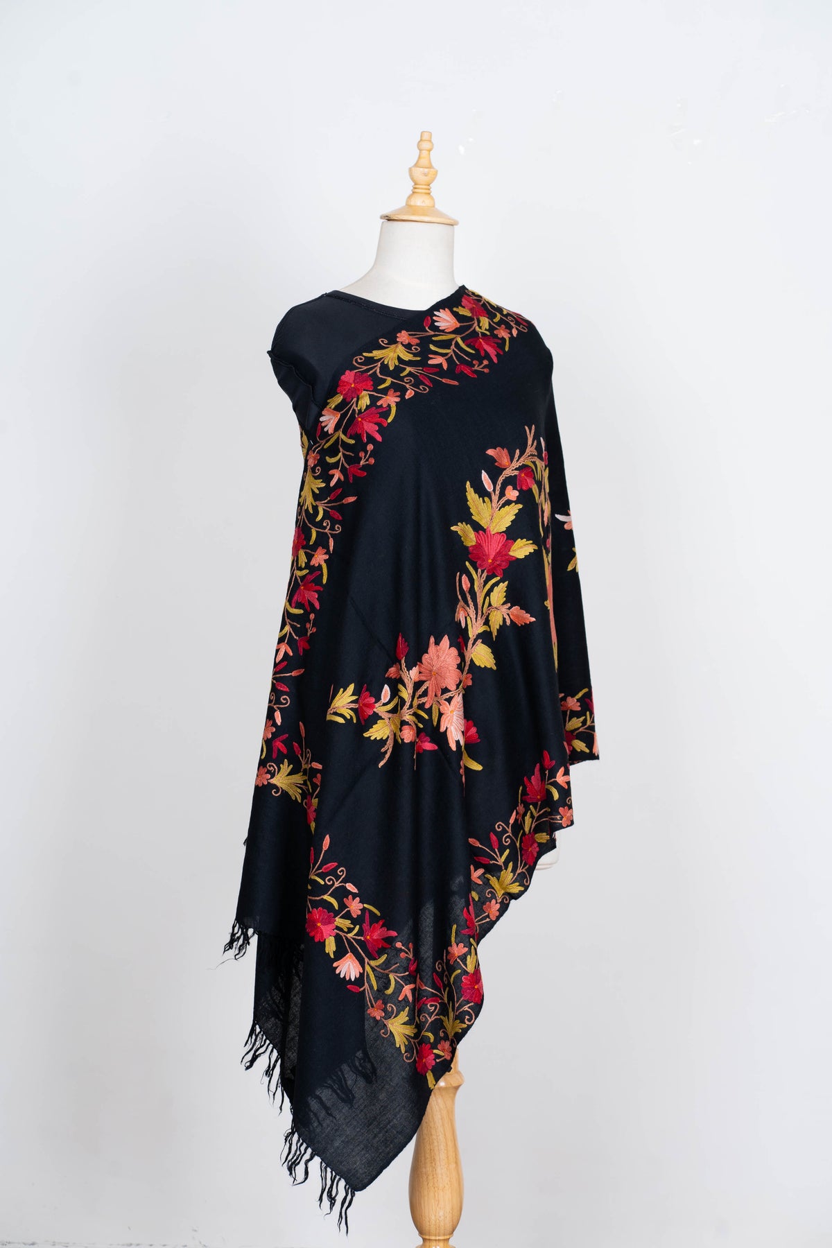 Full drape of the black stole on a mannequin, showing red floral garlands, matching borders and fringed ends.