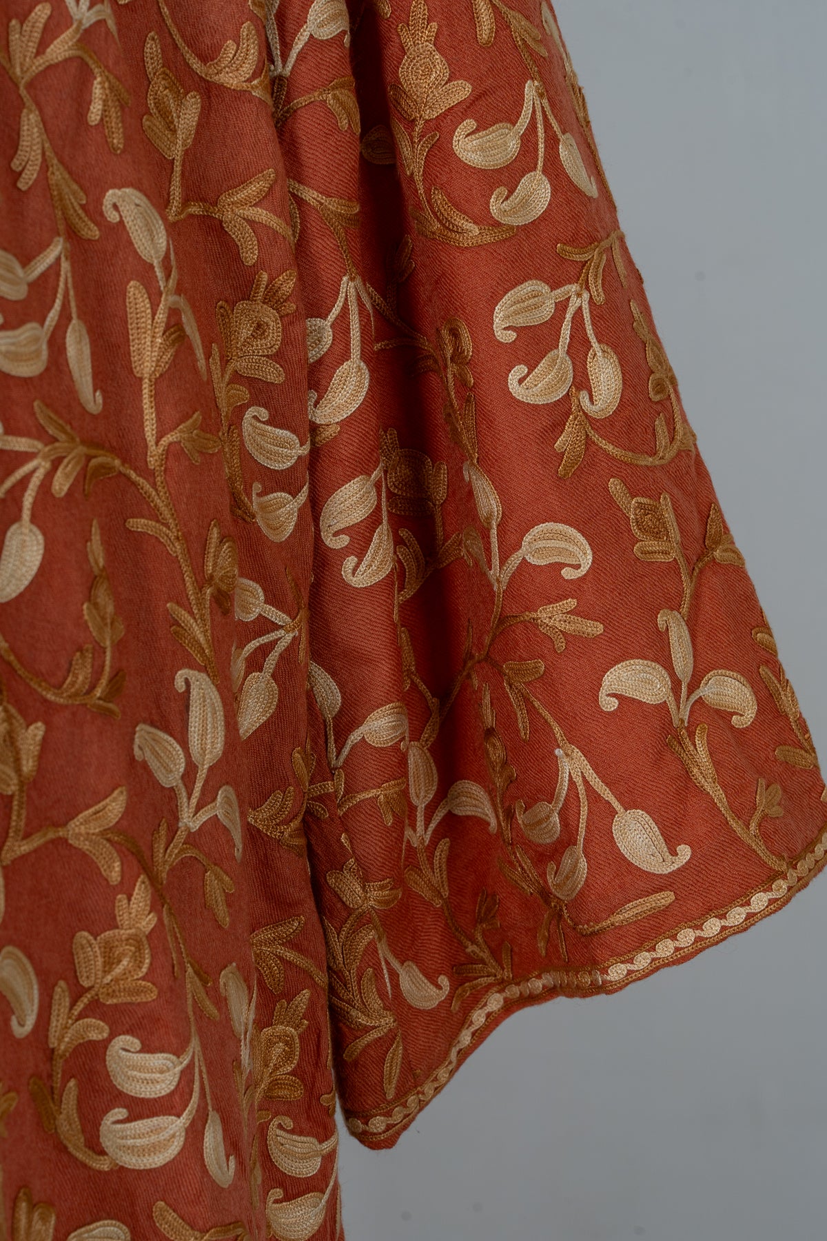 Detail of a burnt-saffron abaya sleeve with cream and gold Aari vines and a narrow looped cuff edging