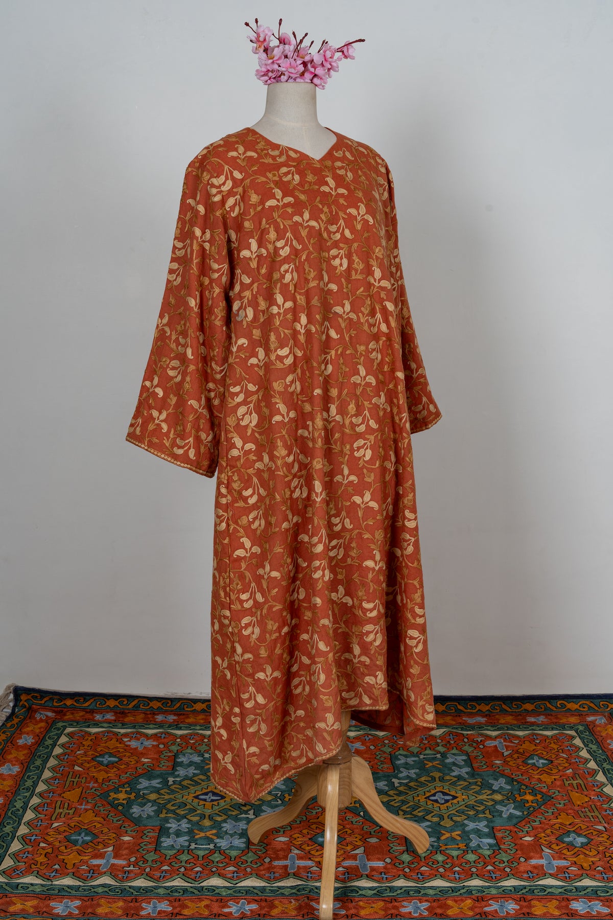 Angled full-length burnt-saffron abaya with cream and gold Aari floral vines and wide embroidered sleeves