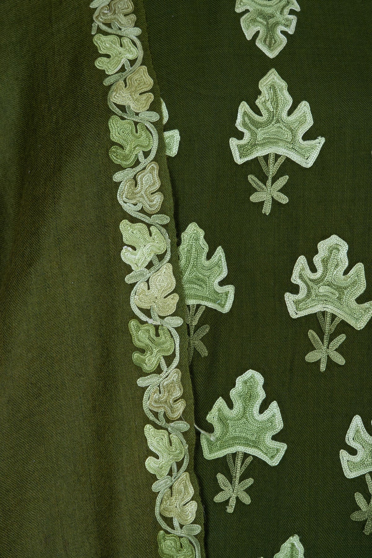 Close-up of the matching olive drape edge with a narrow leafy vine beside the abaya larger leaf motifs.