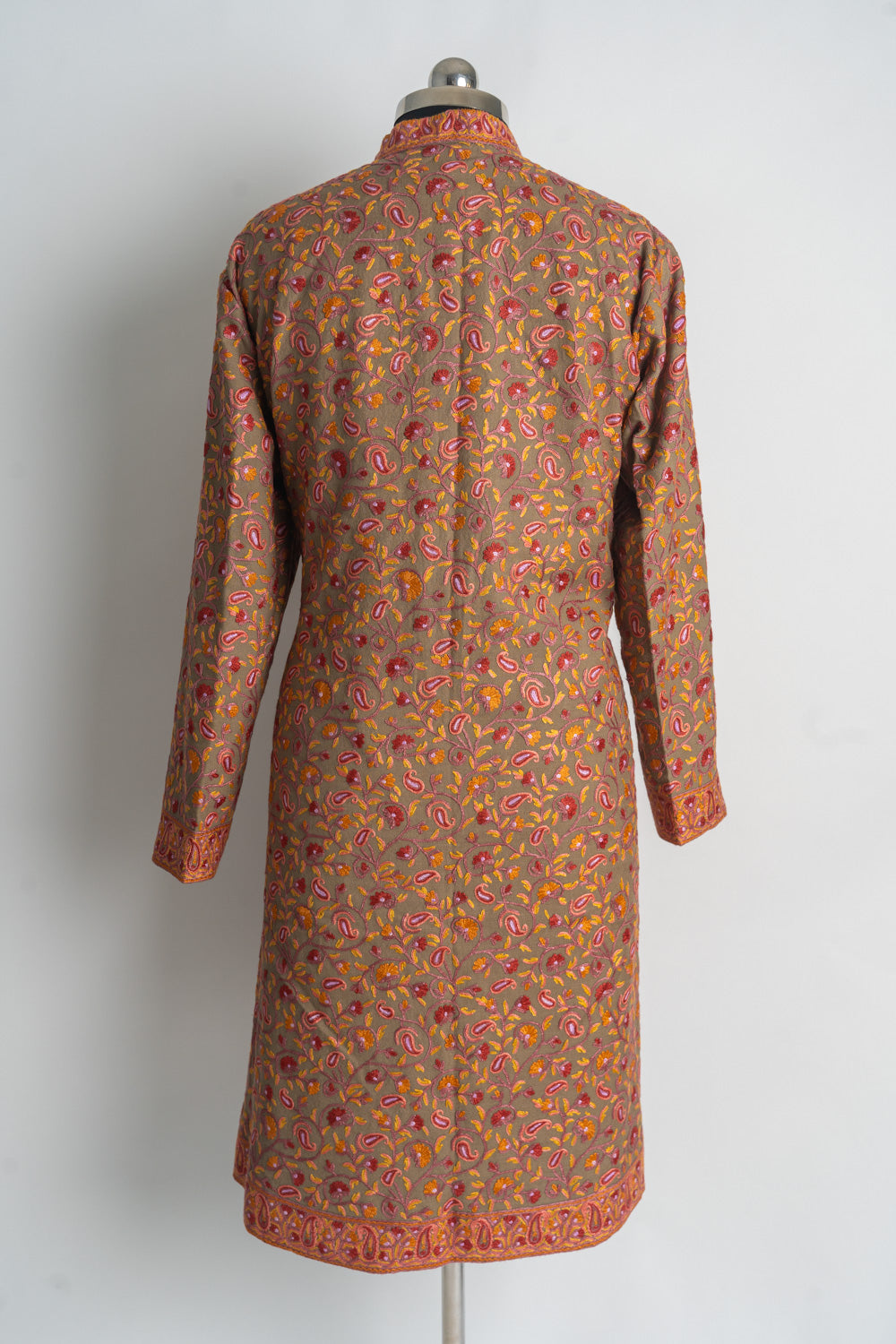 Back of a brown long jacket densely embroidered with pink and orange Aari paisleys and floral vines, with a bordered hem