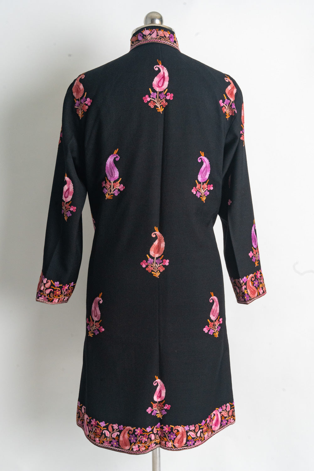 Back of the black Gulab Royale coat with scattered pink paisley sprigs and floral borders at the cuffs and hem
