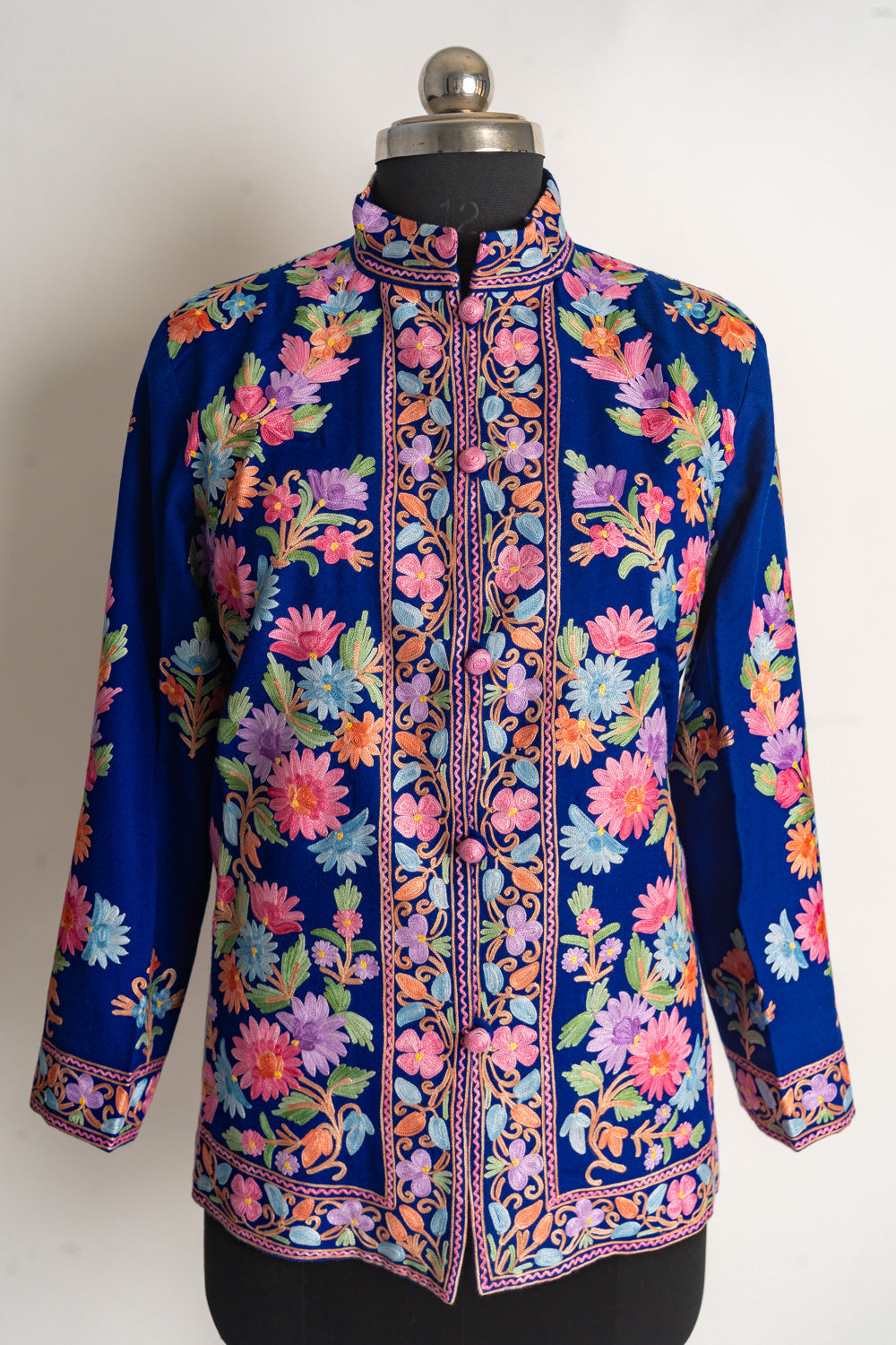 Full front view of a deep-blue jacket covered in pink, purple, orange and light-blue flowers with green leaves.