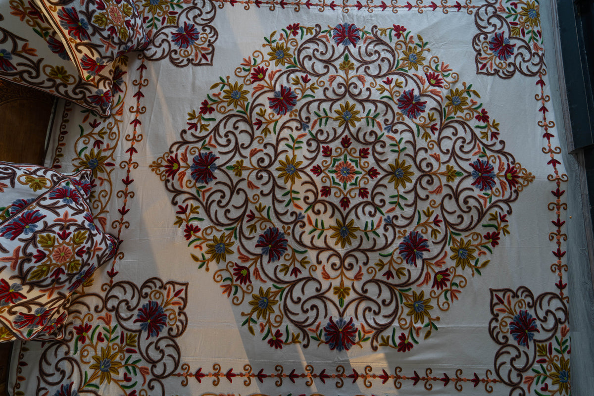 Overhead detail of the bed cover’s large symmetrical Crewel floral medallion, surrounded by corner motifs and a narrow vine border