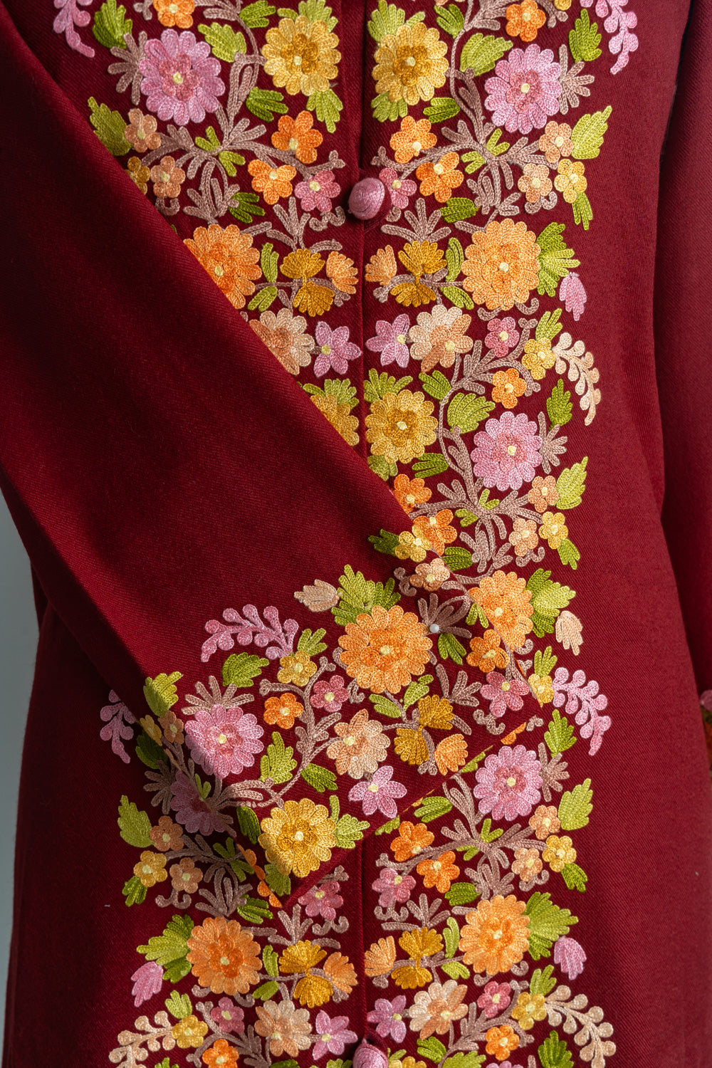 Close-up of the ruby jacket’s crossed cuff beside matching pink and golden-yellow floral embroidery down the front