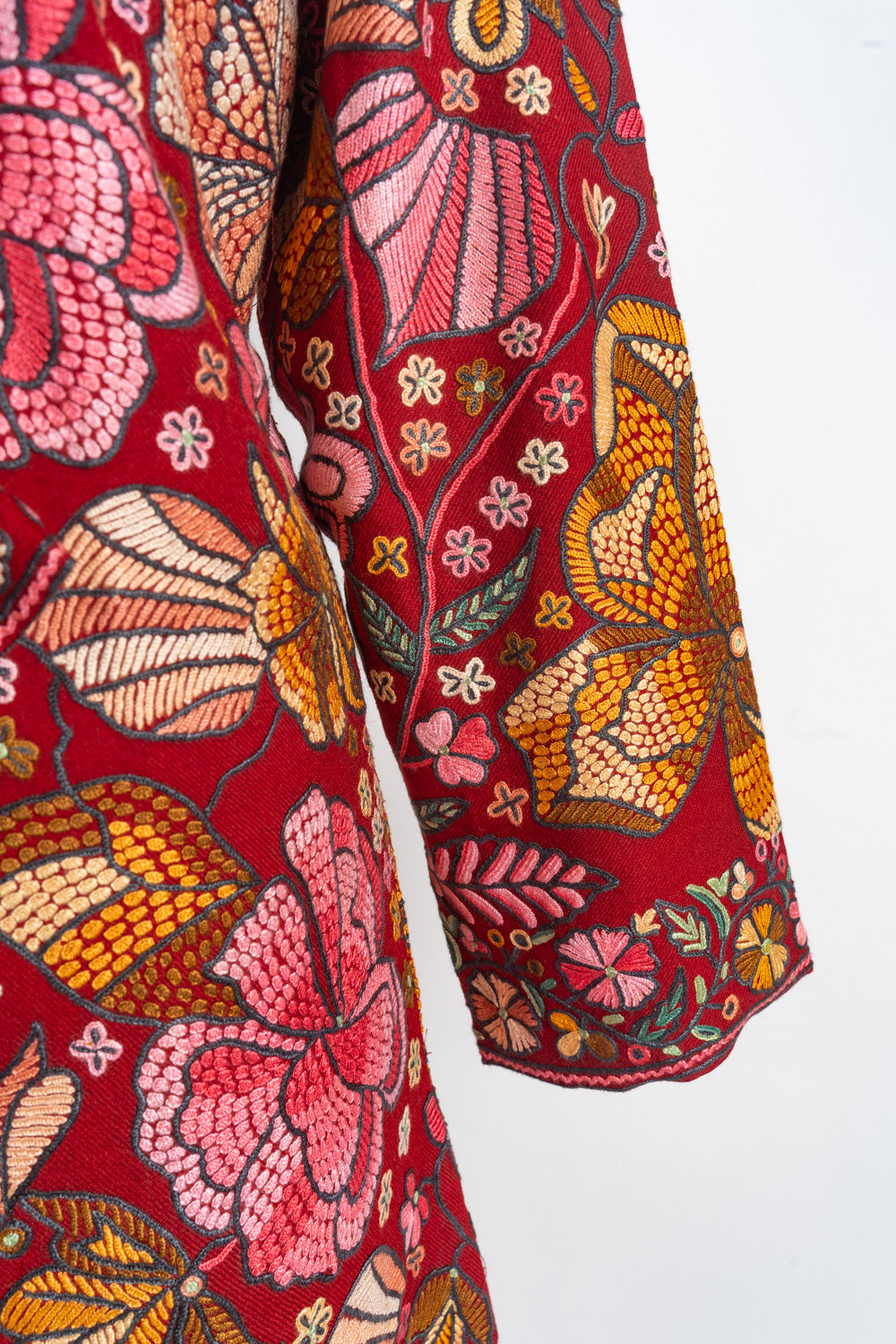 Red jacket sleeve with large pink and orange embroidered flowers and a narrow floral cuff border.
