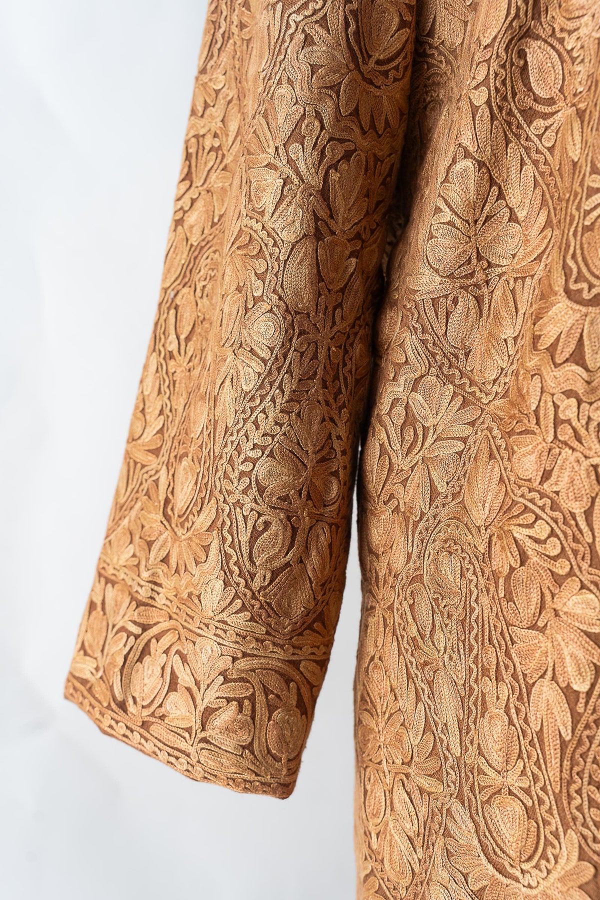 Close-up of the beige jacket's embroidered sleeve and floral cuff border beside the patterned body