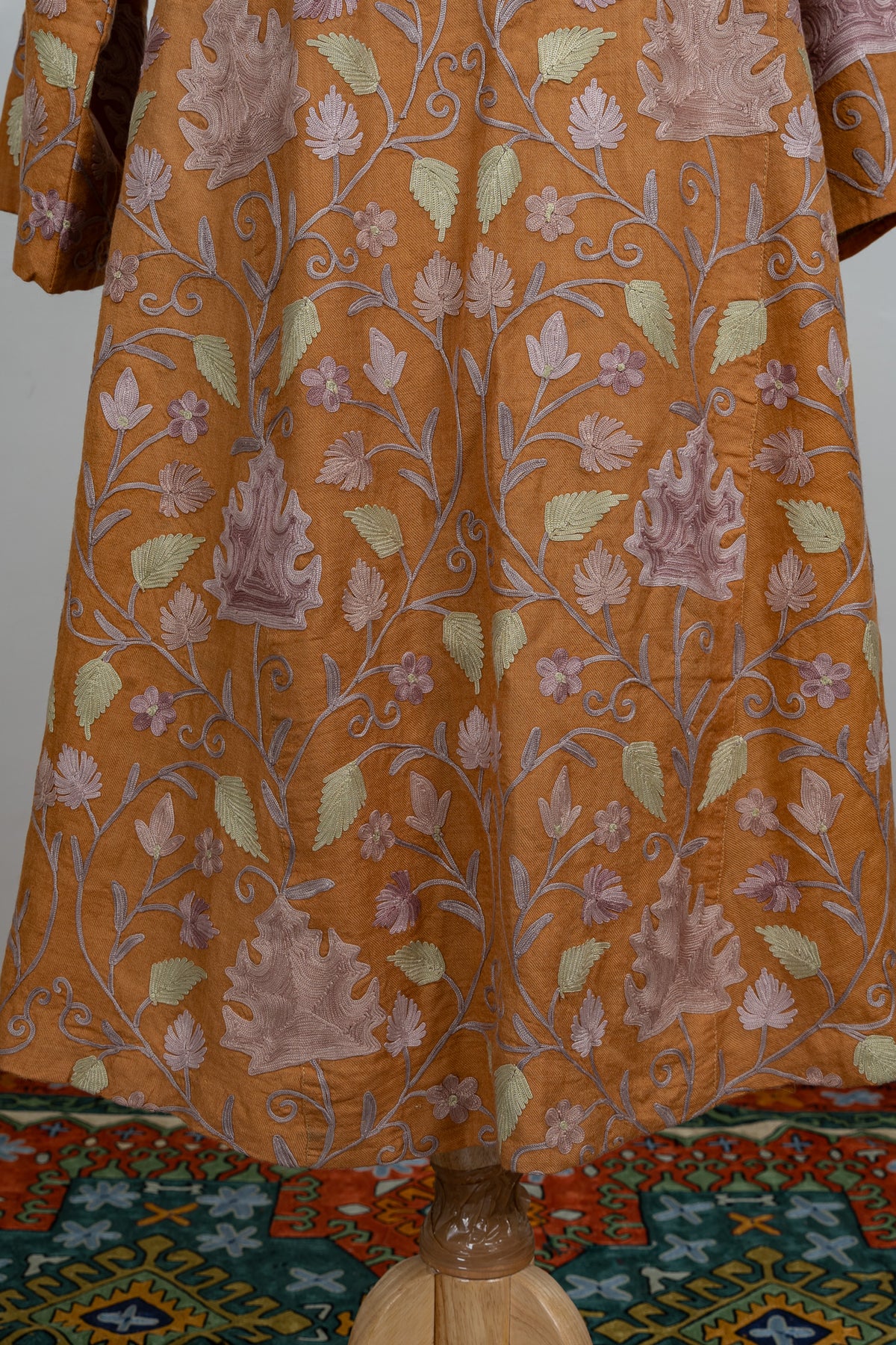 Lower front of an amber abaya covered in pale lilac and green Aari leaves linked by curling vines