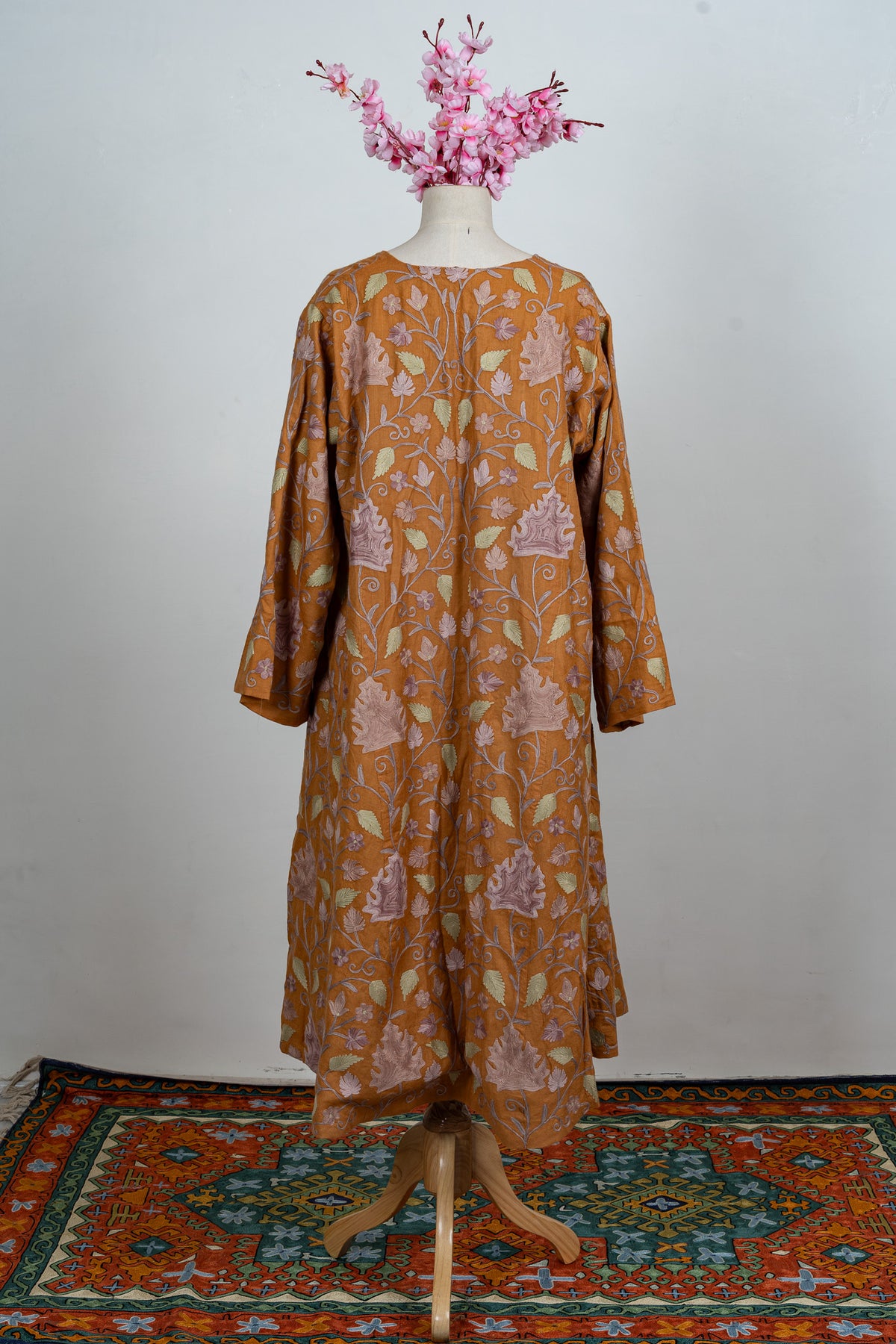 Full-length back of an amber abaya with all-over pale lilac and green Aari foliage and wide sleeves