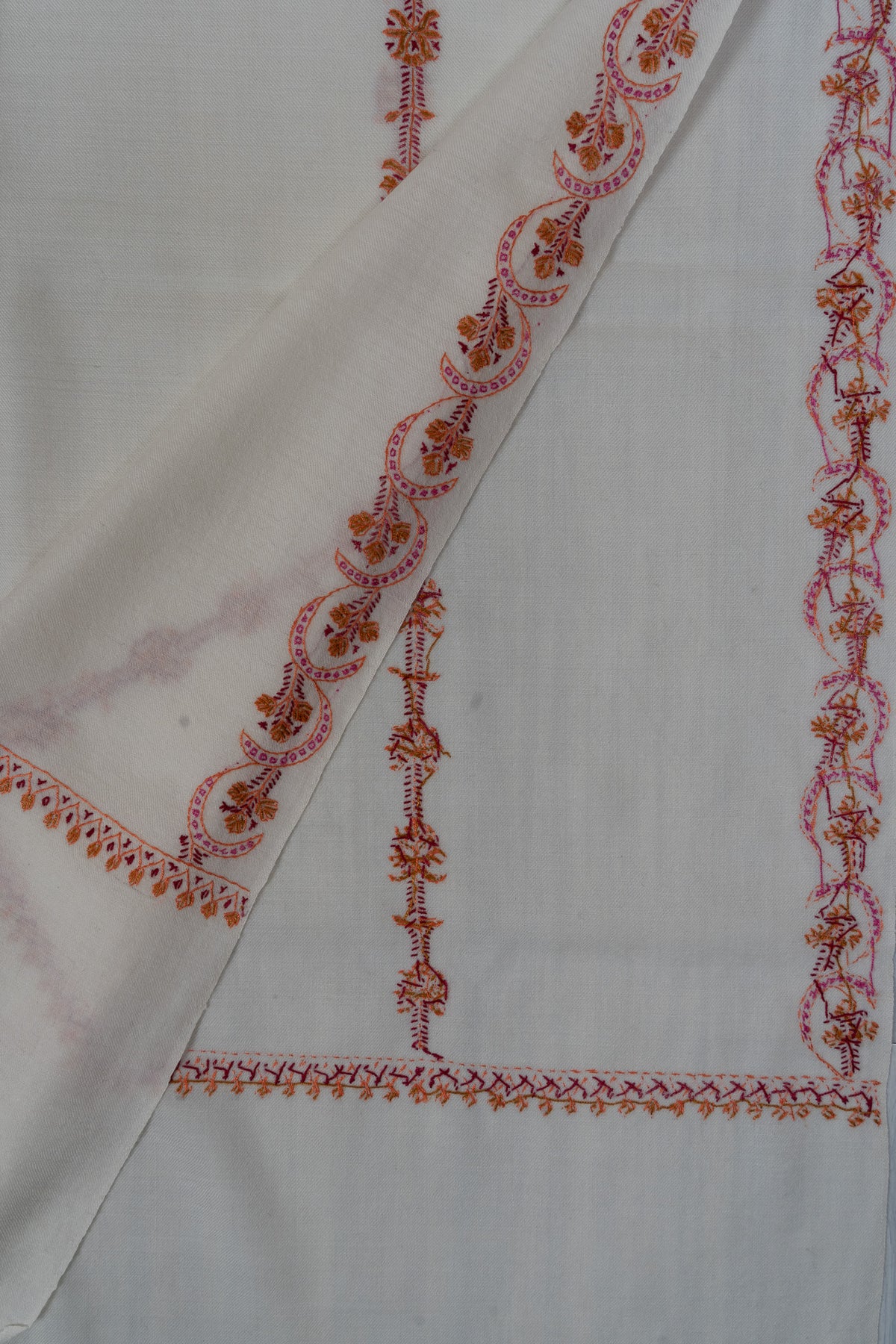 Folded ivory shawl corner showing both sides of pink and orange Sozni floral stripes and end-border stitching