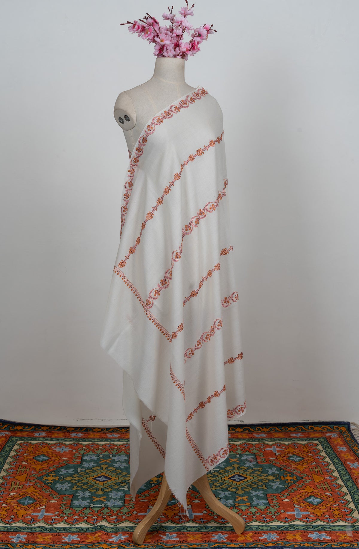 Full-length ivory shawl on a mannequin with alternating pink and orange Sozni floral stripes and plain end bands