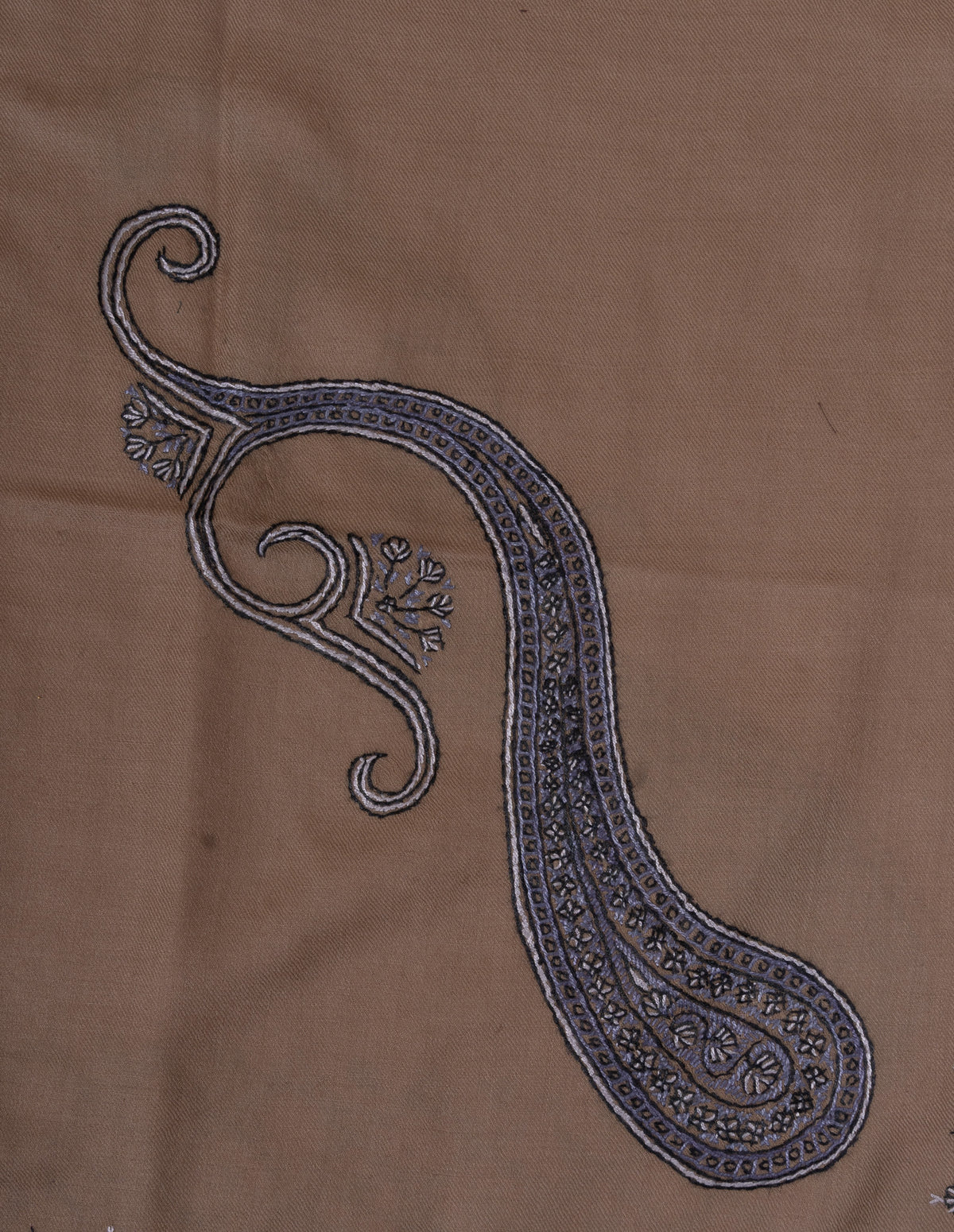 Close-up of a large blue-grey Sozni paisley filled with fine floral details on desert-beige fabric
