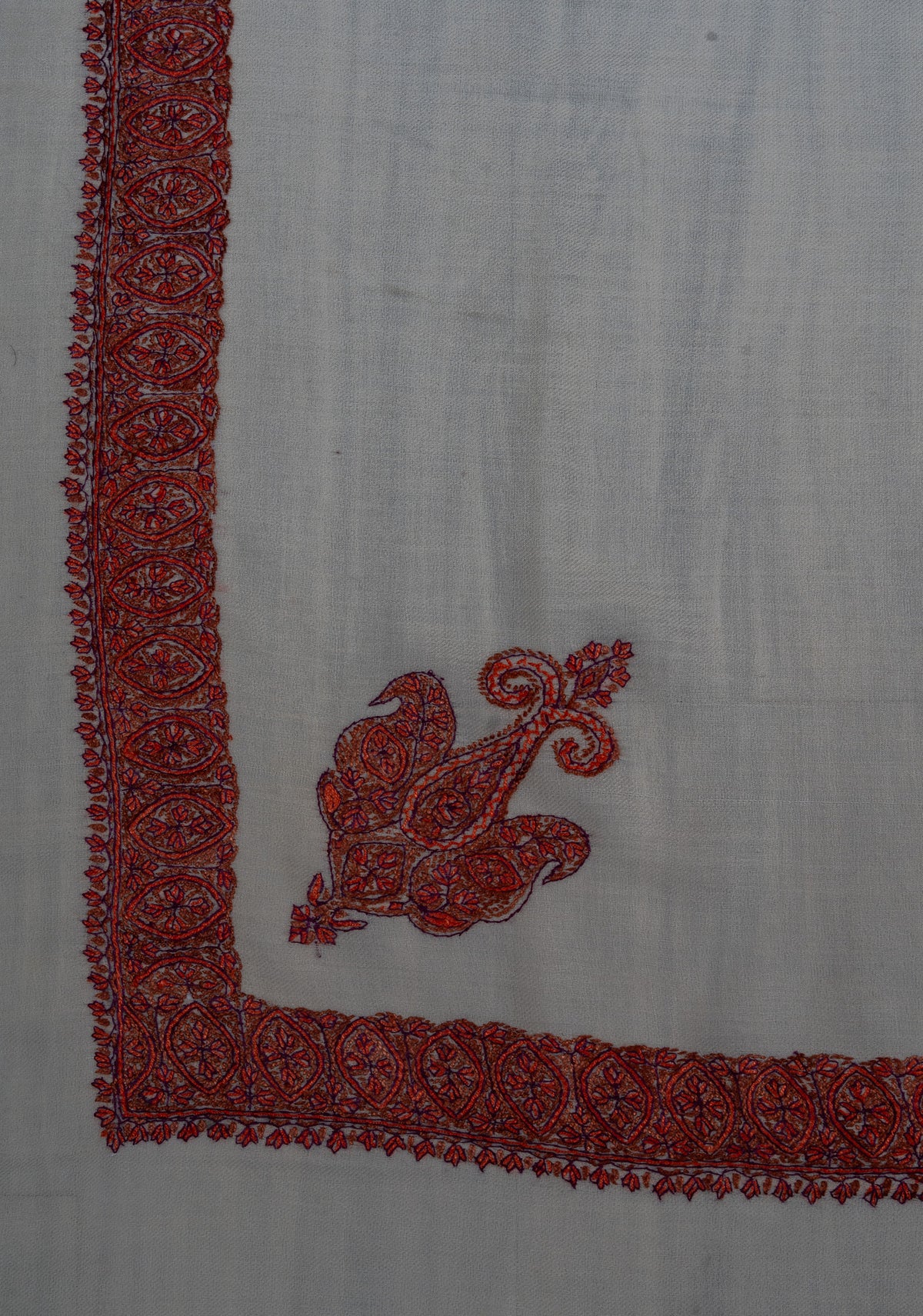 Ivory rumal corner with a ruby-red Sozni paisley inside a narrow border of floral medallions