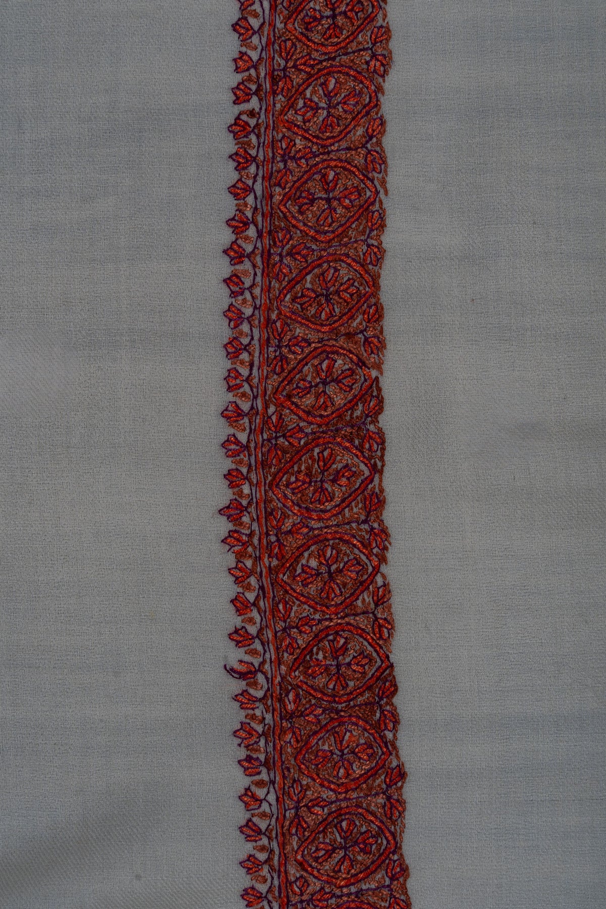 Ruby-red Sozni floral medallions with dark outlines and small leaf edging along an ivory rumal border