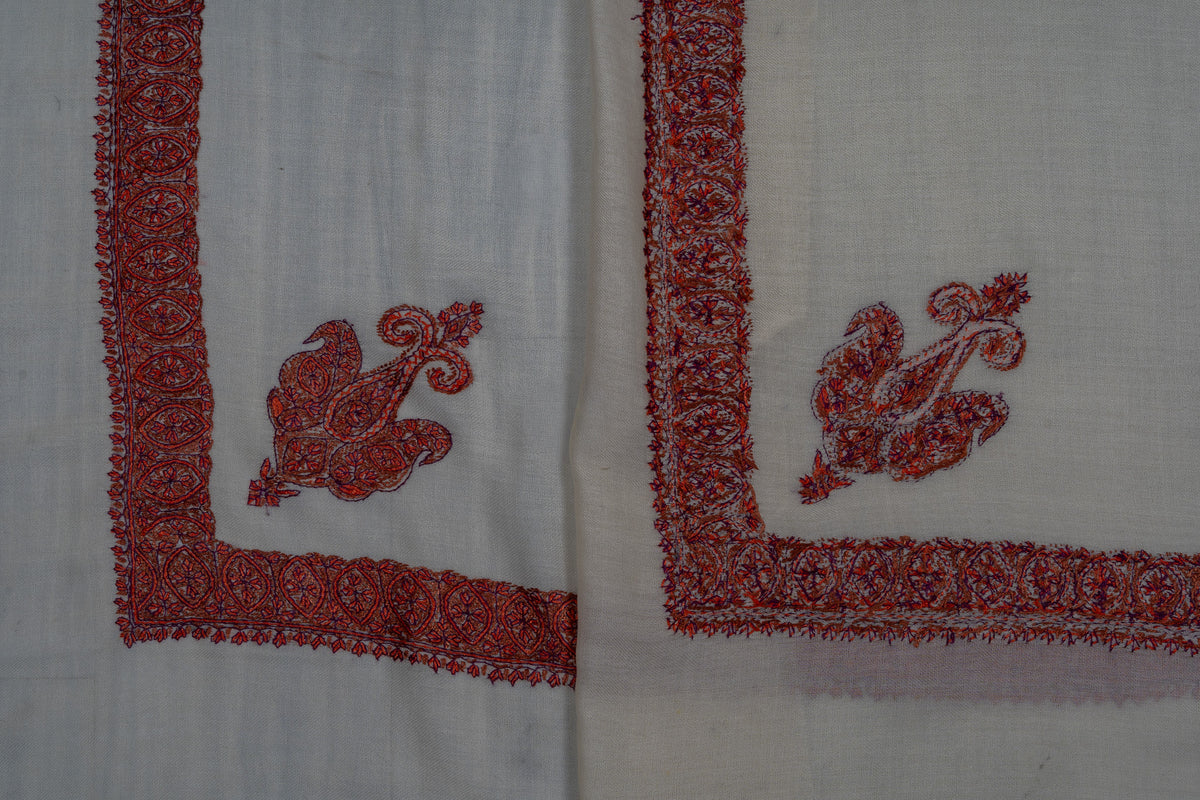 Folded ivory rumal showing both sides of ruby-red Sozni corner paisleys and floral borders