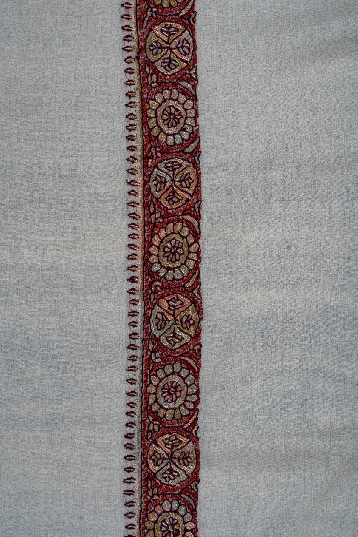 Close-up of an ivory rumal border with crimson, gold and pale pink flower and leaf medallions and a narrow pointed edging