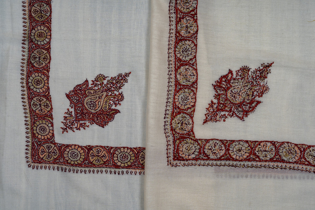 Overlapping ivory rumal corners, showing both sides of crimson and gold Sozni floral motifs and medallion borders