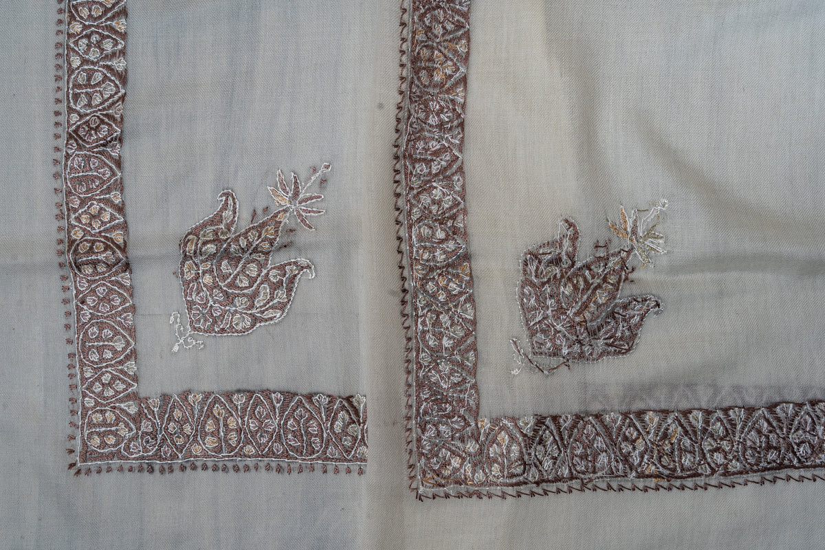 Overlapping ivory rumal corners, showing both sides of mocha and ivory Sozni floral motifs and geometric borders