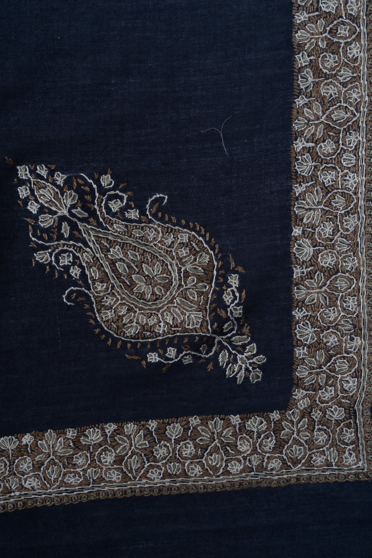 Close-up of a navy rumal corner with a gold and ivory Sozni paisley beside the floral border