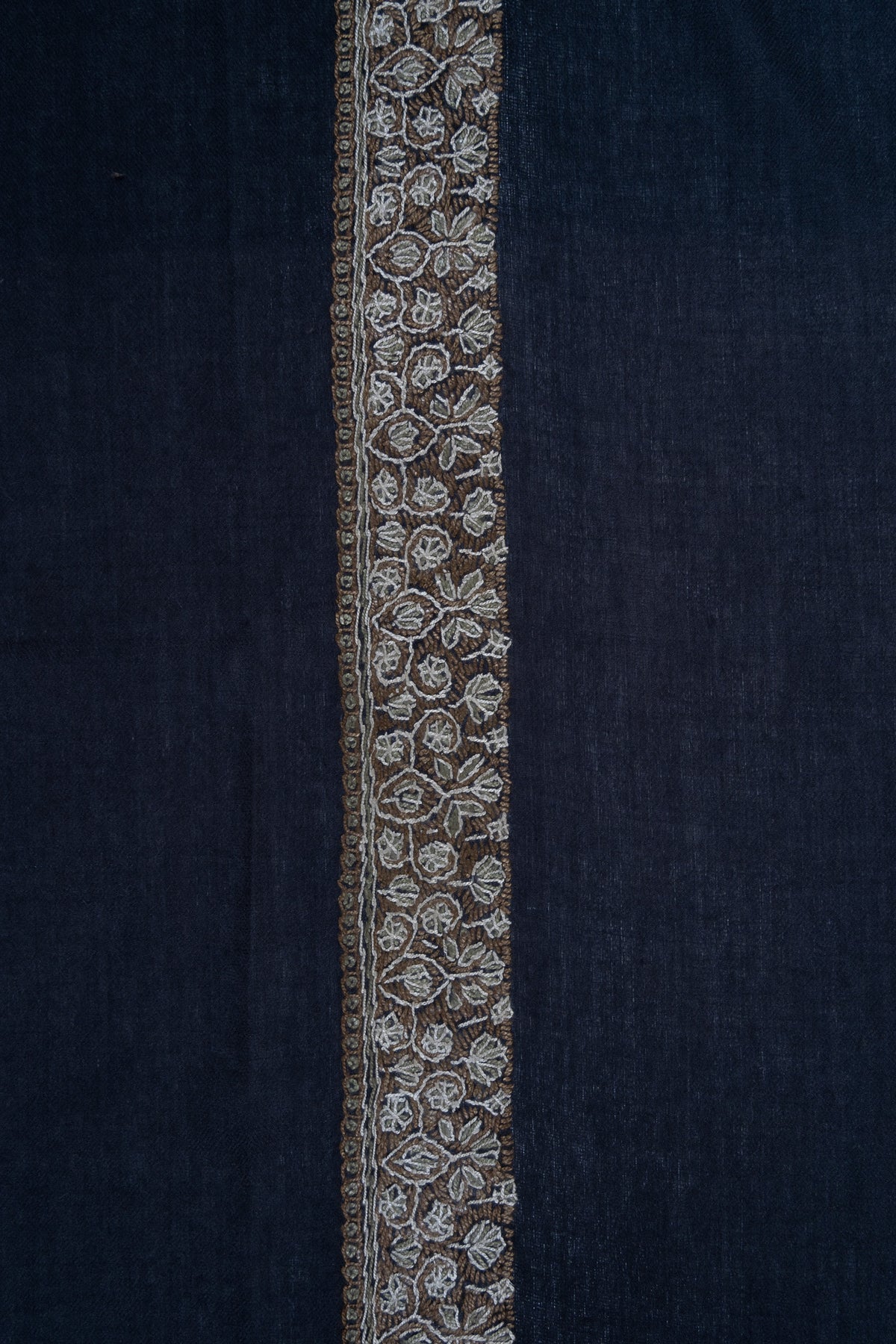 Close-up of a narrow gold and ivory Sozni floral border along a navy rumal