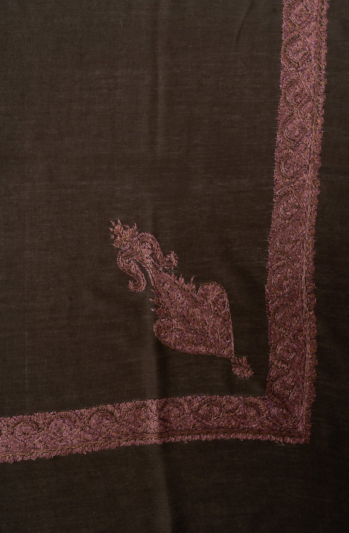 Corner of a dark brown Merino wool rumal with a rose-gold Sozni paisley and floral edging.