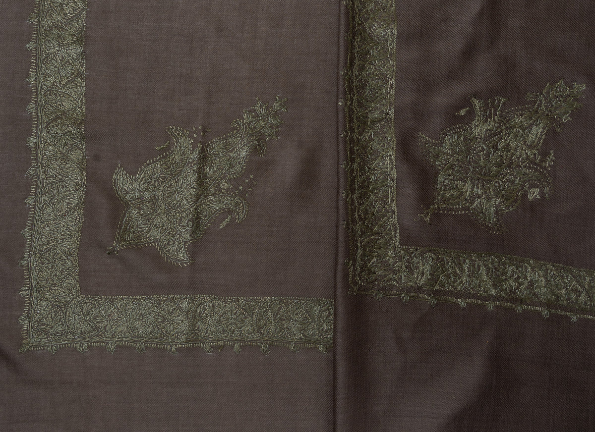 Overlapping corners of a smoky-brown Merino wool rumal with olive-green Sozni motifs and borders.