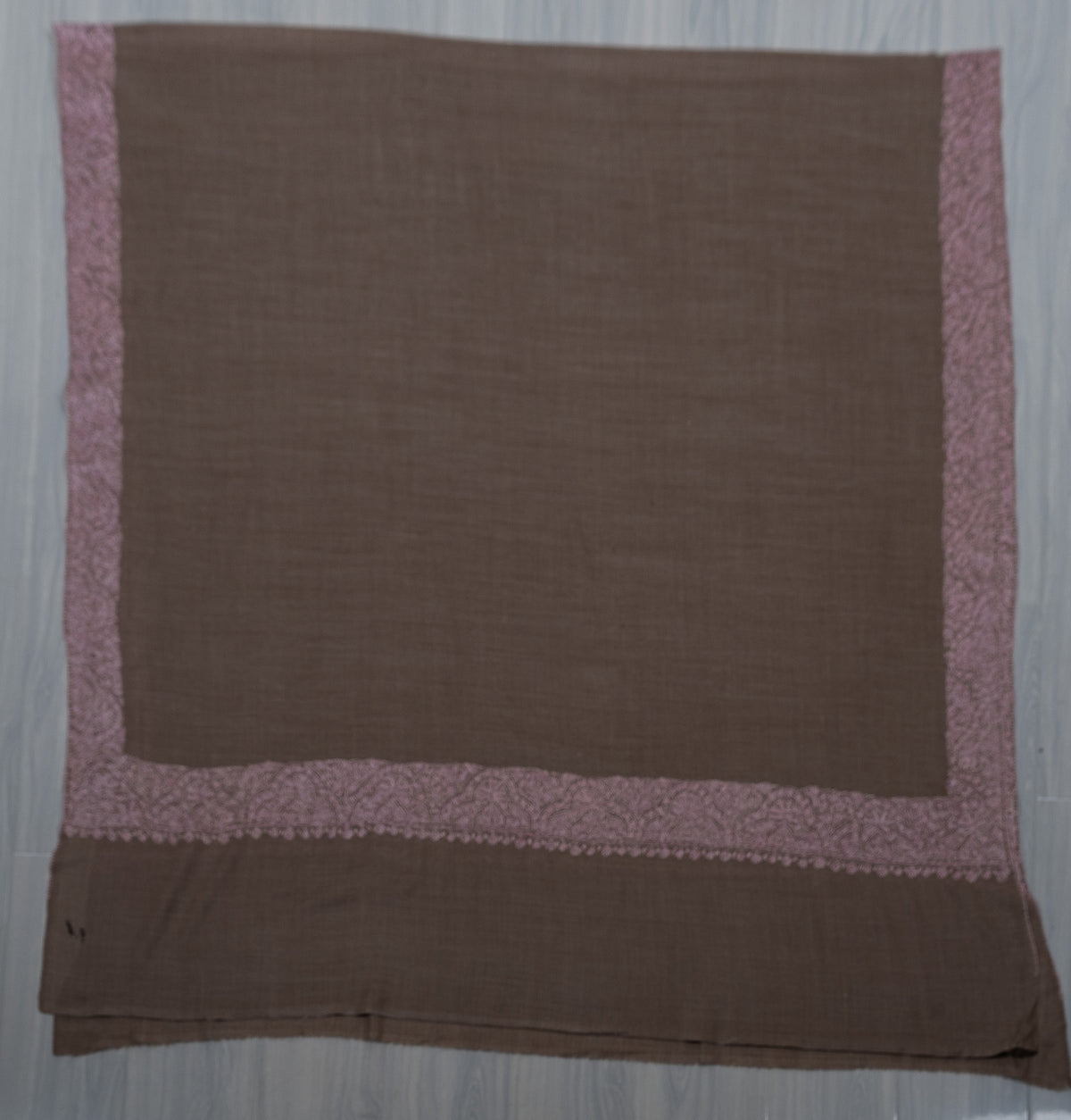 Taupe Merino wool shawl laid flat with blush-pink Sozni borders framing a plain centre and end panel.