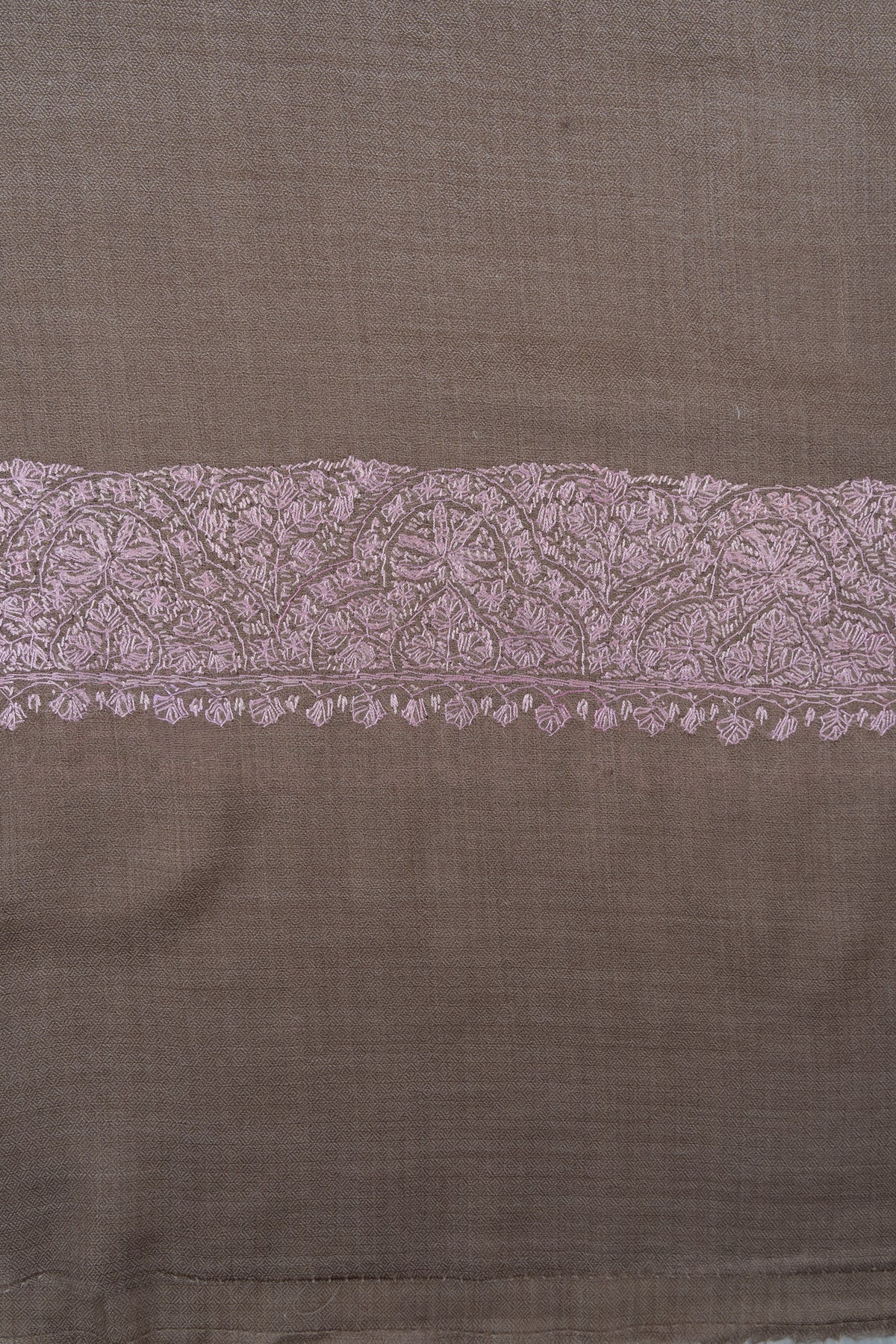 Close-up of a blush-pink Sozni floral border with tiny leaf edging on taupe Merino wool.