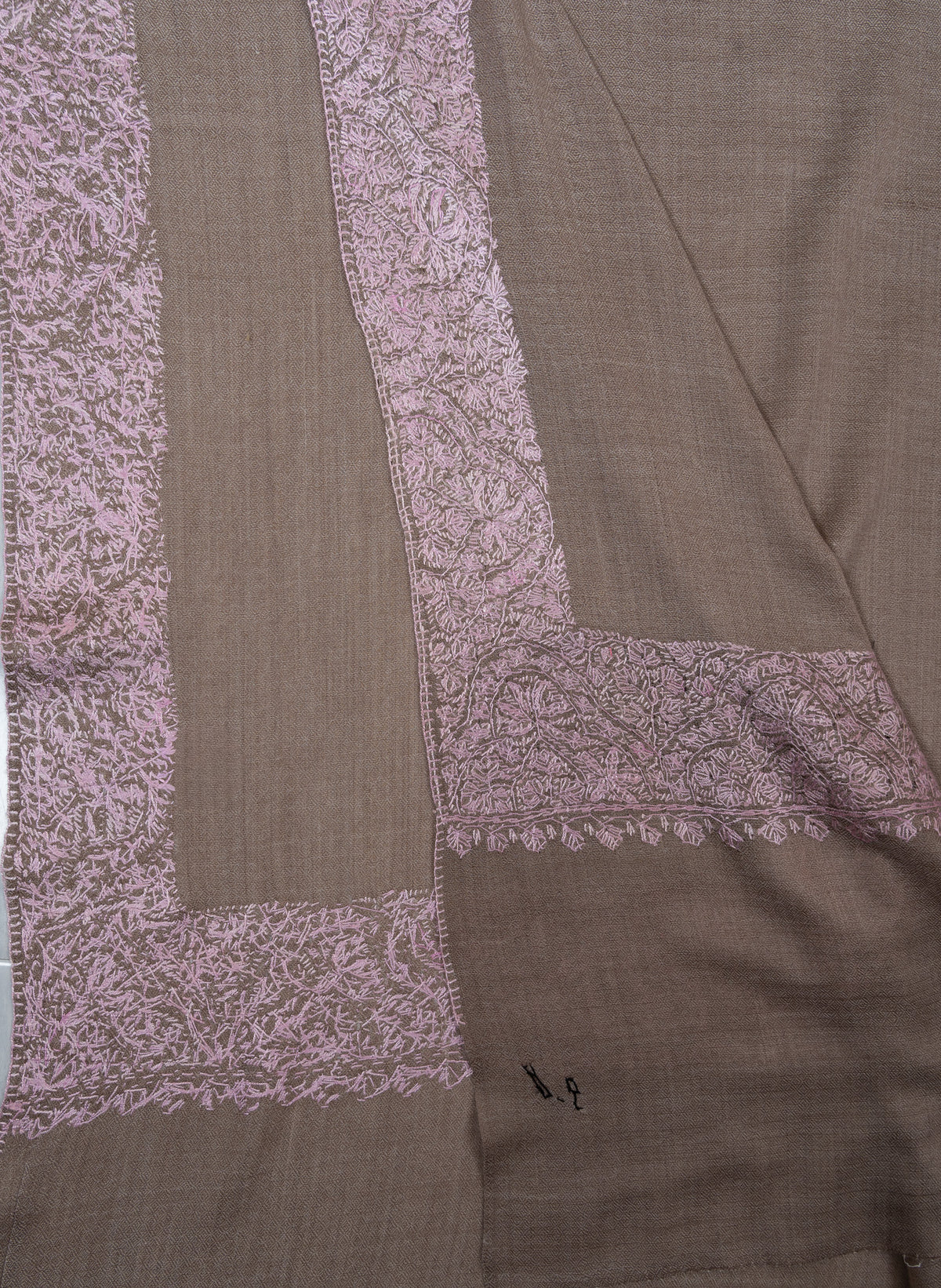 Overlapping corners showing the front and reverse of blush-pink Sozni border stitching on taupe Merino wool.