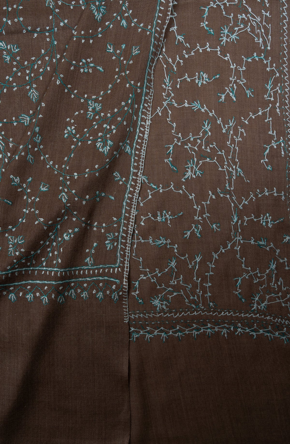 Folded cocoa-brown shawl corner showing both sides of pale aqua Sozni floral vines and narrow borders
