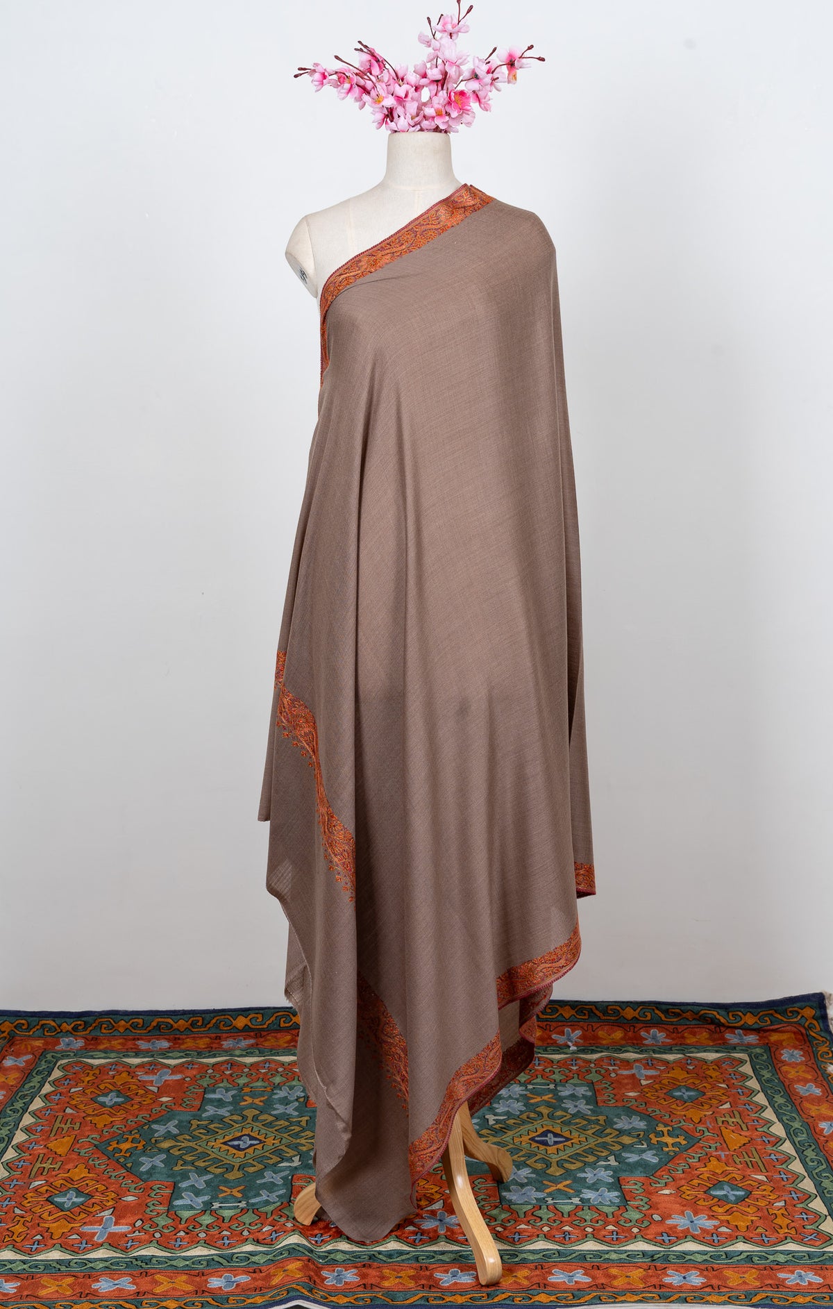 Front view of a truffle-brown shawl draped over one shoulder, with rust-orange borders and a plain field