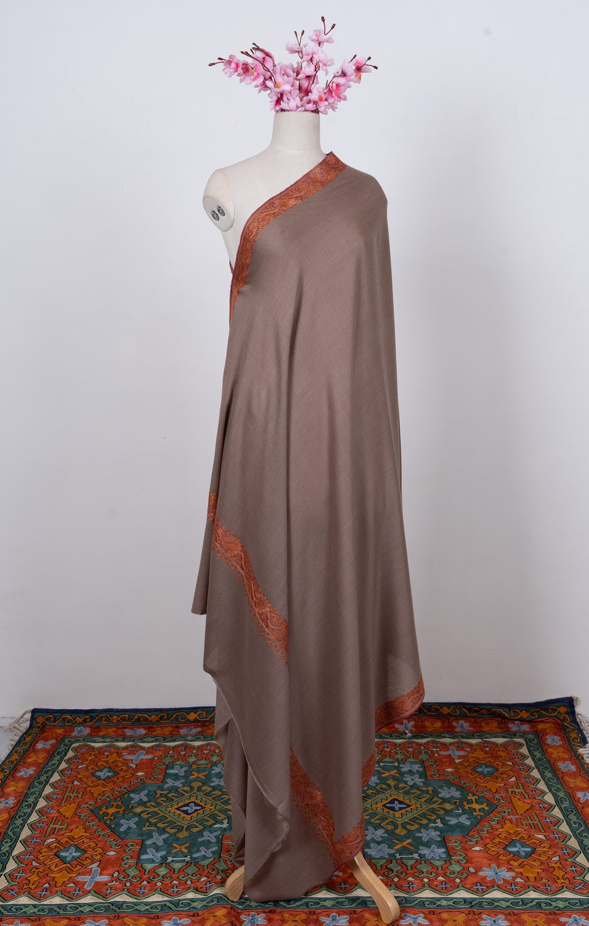 Full-length truffle-brown Merino wool shawl draped on a mannequin with rust-orange borders
