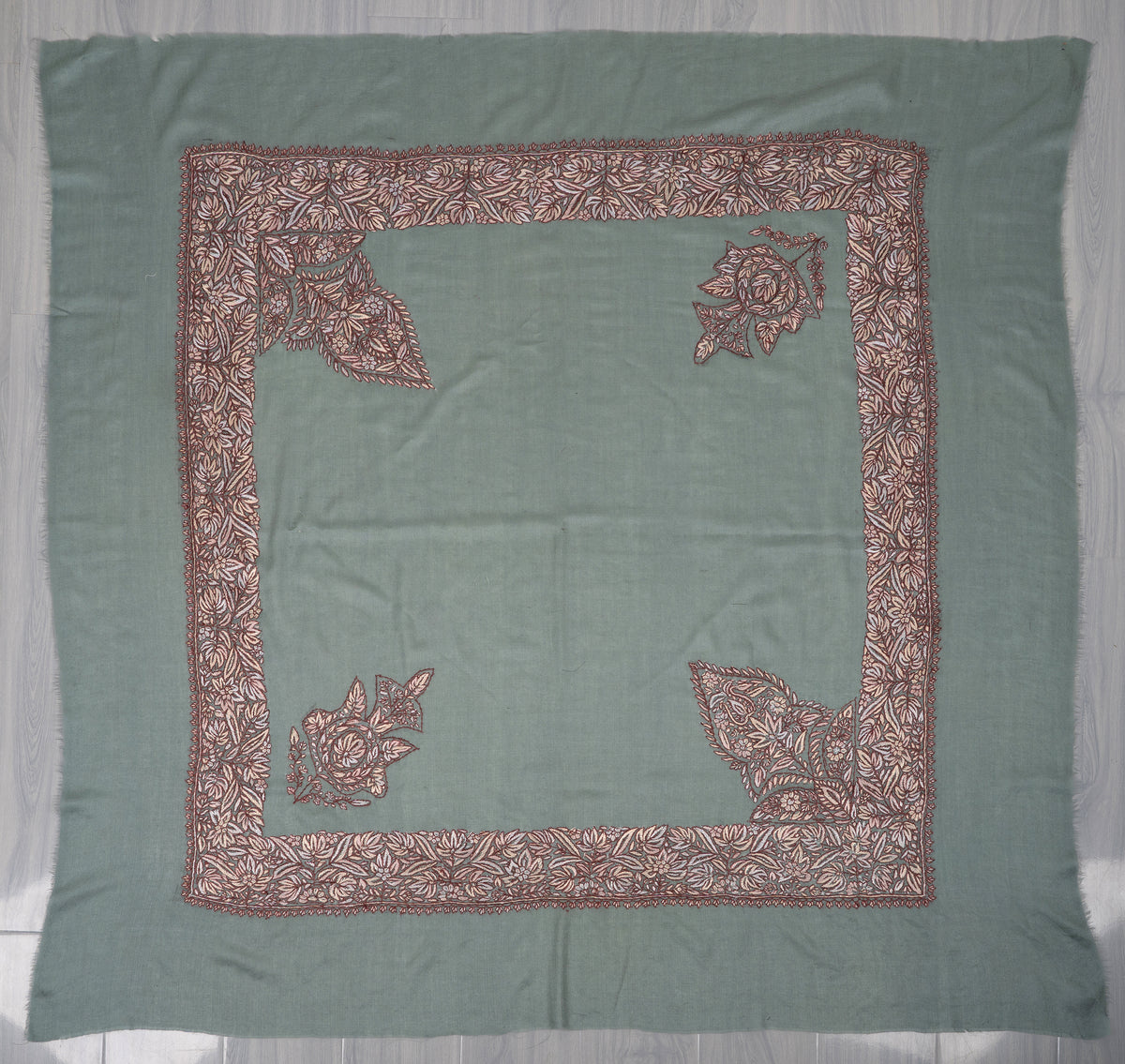 Square sage-green rumal spread flat, with a plain centre, cream-brown floral border and four corner motifs