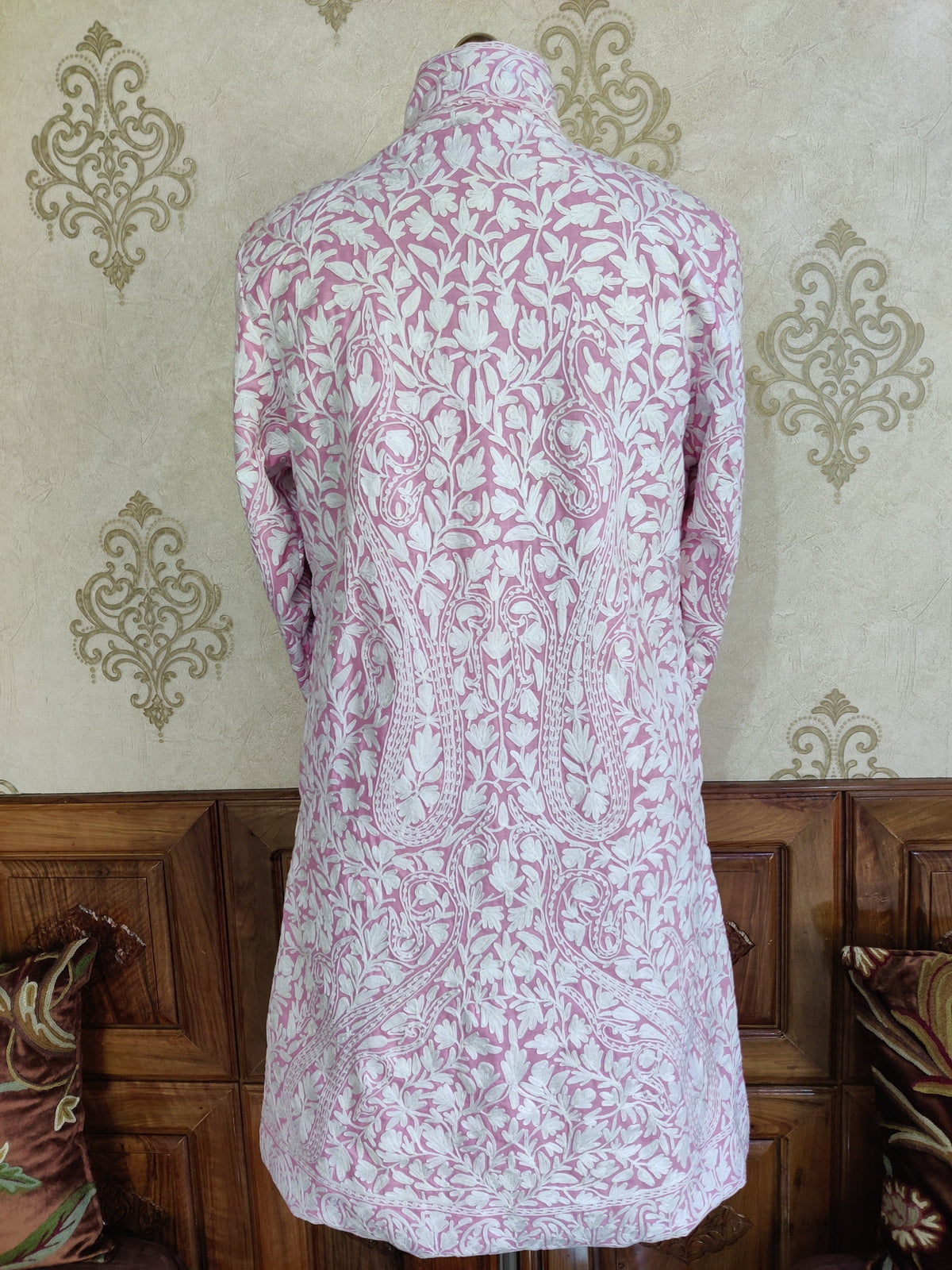 Back of a pale-pink jacket covered in symmetrical white floral vines and large paisley motifs.