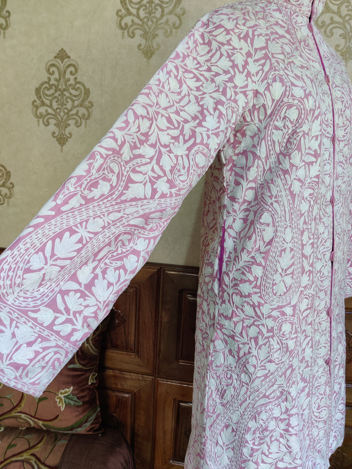 Extended sleeve detail of the pale-pink jacket, showing white leafy vines and large paisleys.