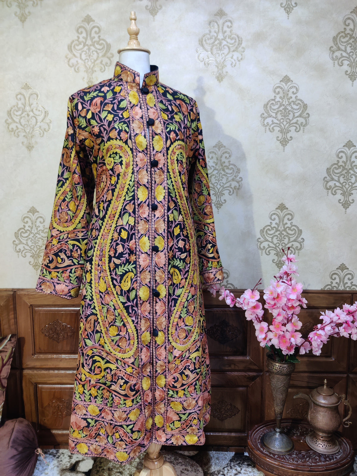 Full front of a dark Fall Fiesta jacket with large yellow-green Aari paisleys, pink and brown flowers and black buttons