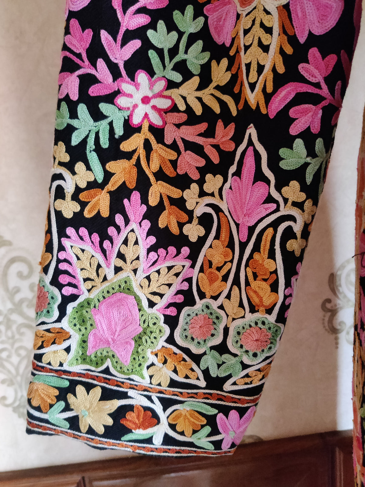 Black jacket sleeve detail with multicoloured Aari leafy sprigs and a broad pink-green floral cuff