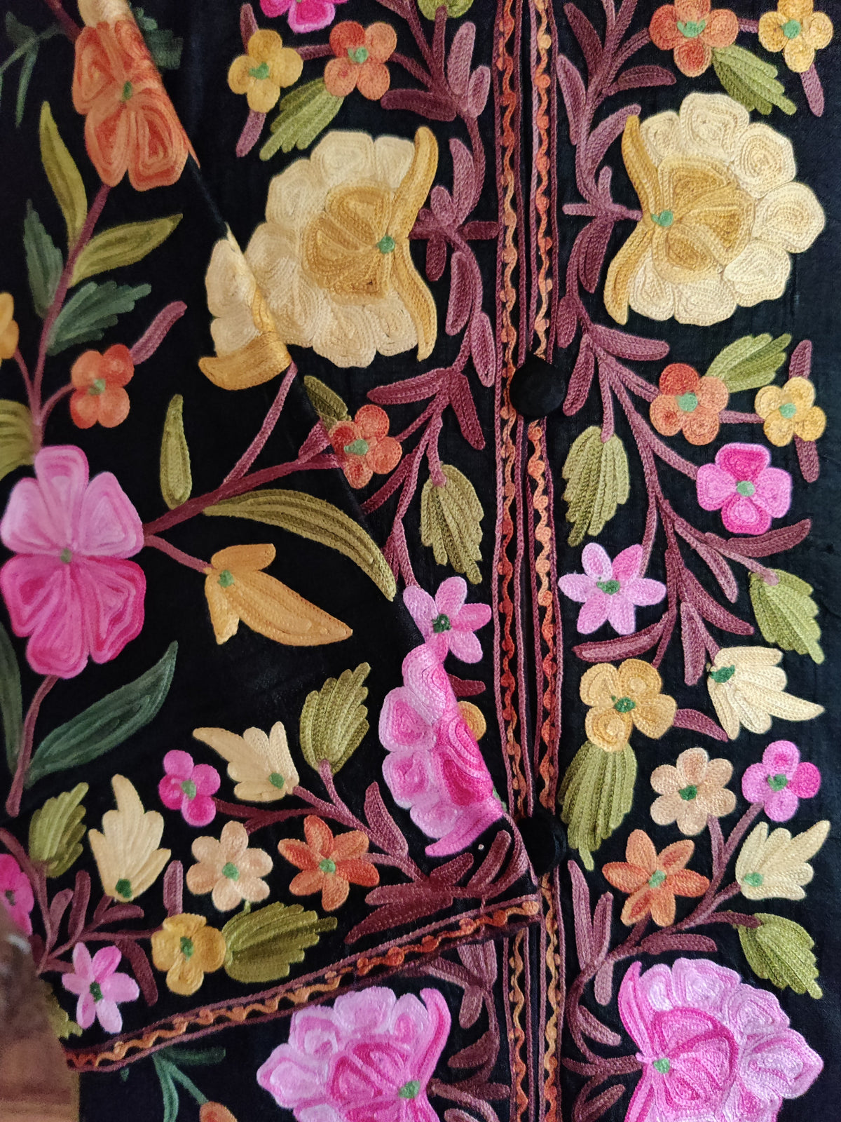 Black jacket front and folded cuff with pink, yellow and orange Aari flowers, green leaves and mauve branching stems