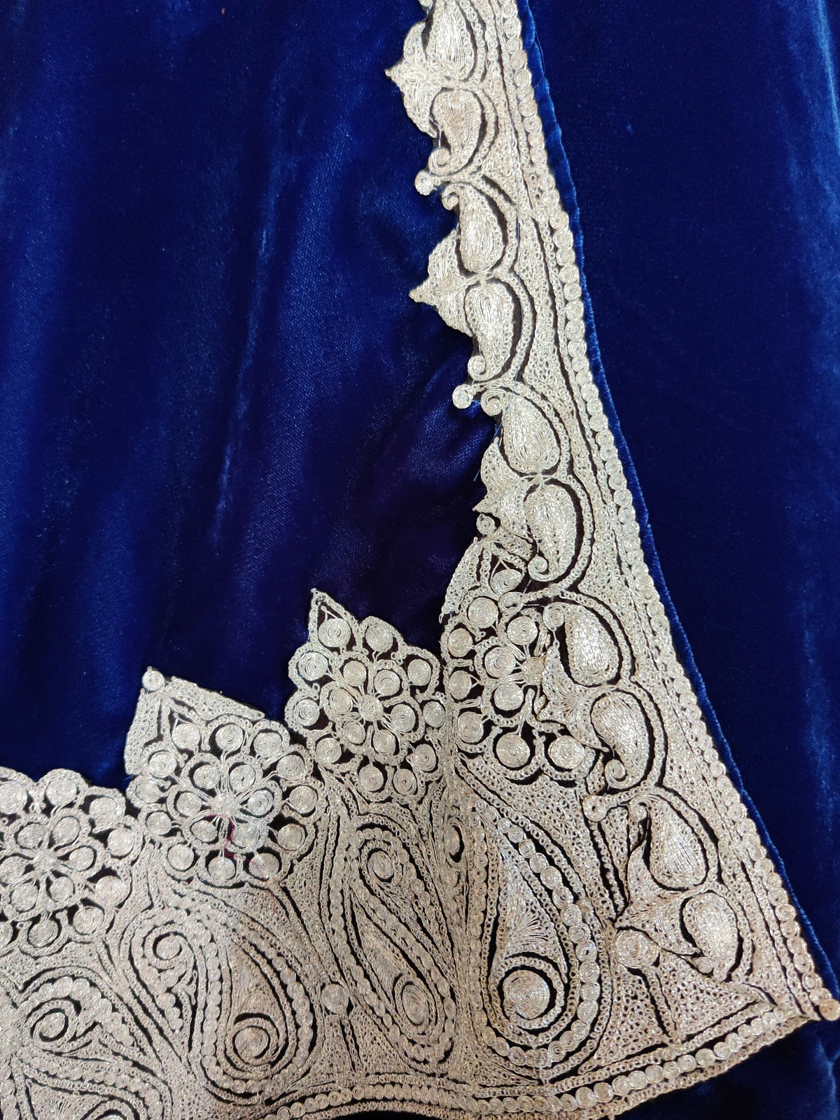 Corner of the blue velvet stole with silver-toned paisley and rosette embroidery and a narrow scrolling side border.