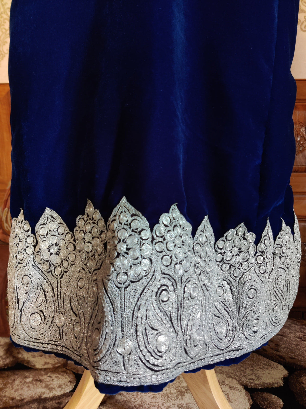 Close-up of the blue velvet pheran hem with silver-toned paisleys, round flowers and pointed edging.