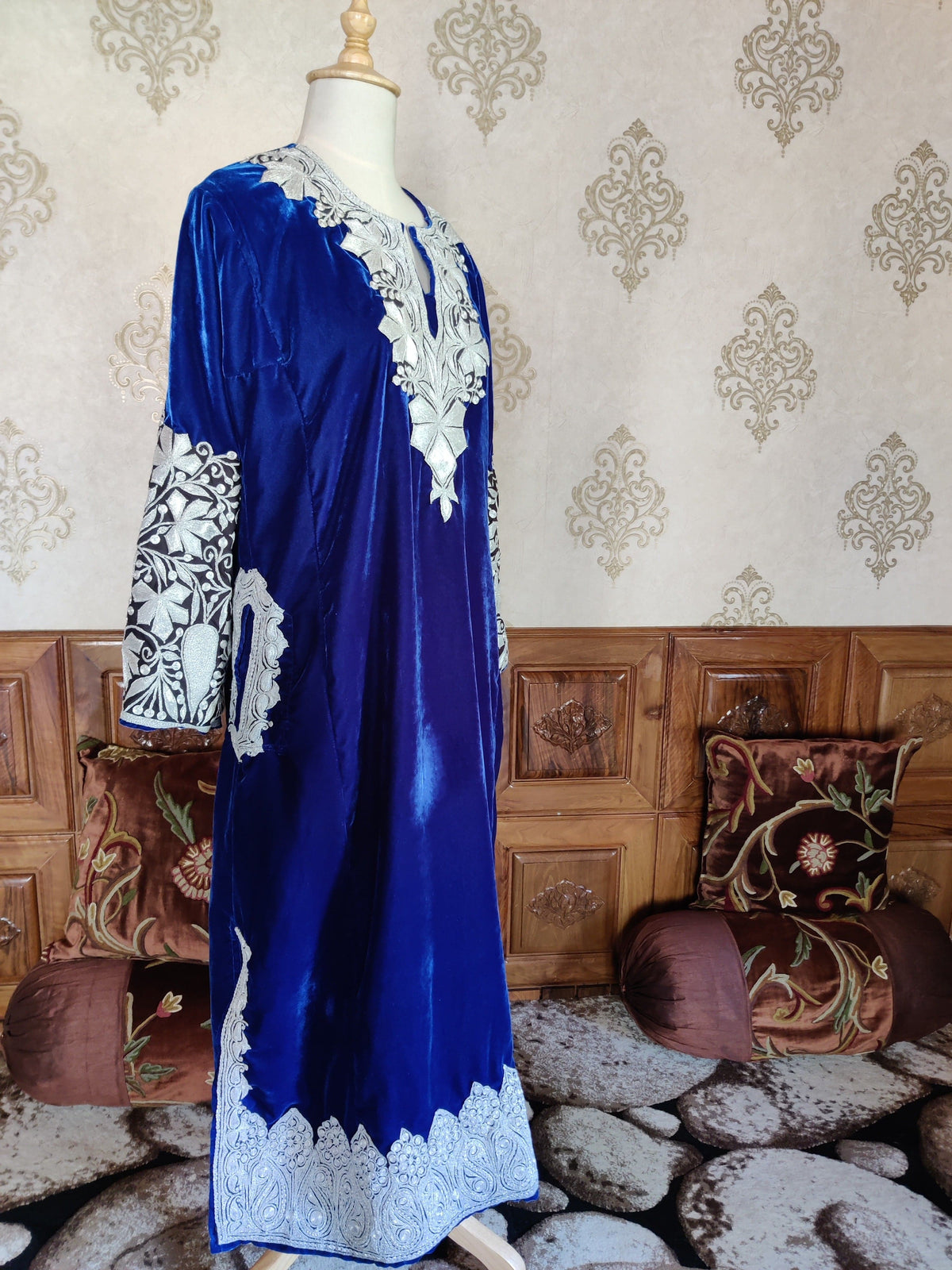 Side view of the blue velvet pheran showing silver-toned embroidery at the neckline, cuff, pocket opening and hem.