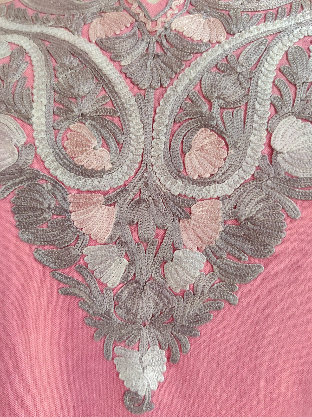 Close-up of grey, cream and pale pink Aari paisleys and layered flowers at the point of a pink kurti neckline