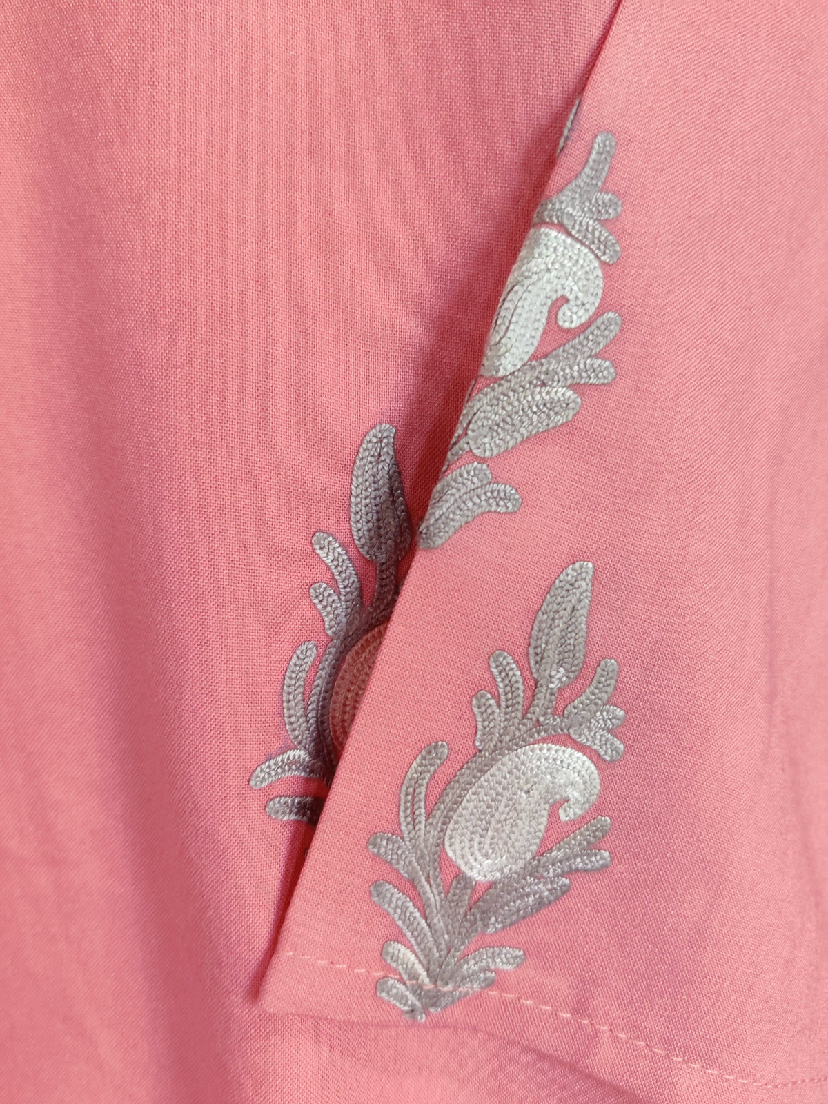 Pink kurti sleeve detail with small grey and cream Aari floral motifs near the plain stitched cuff