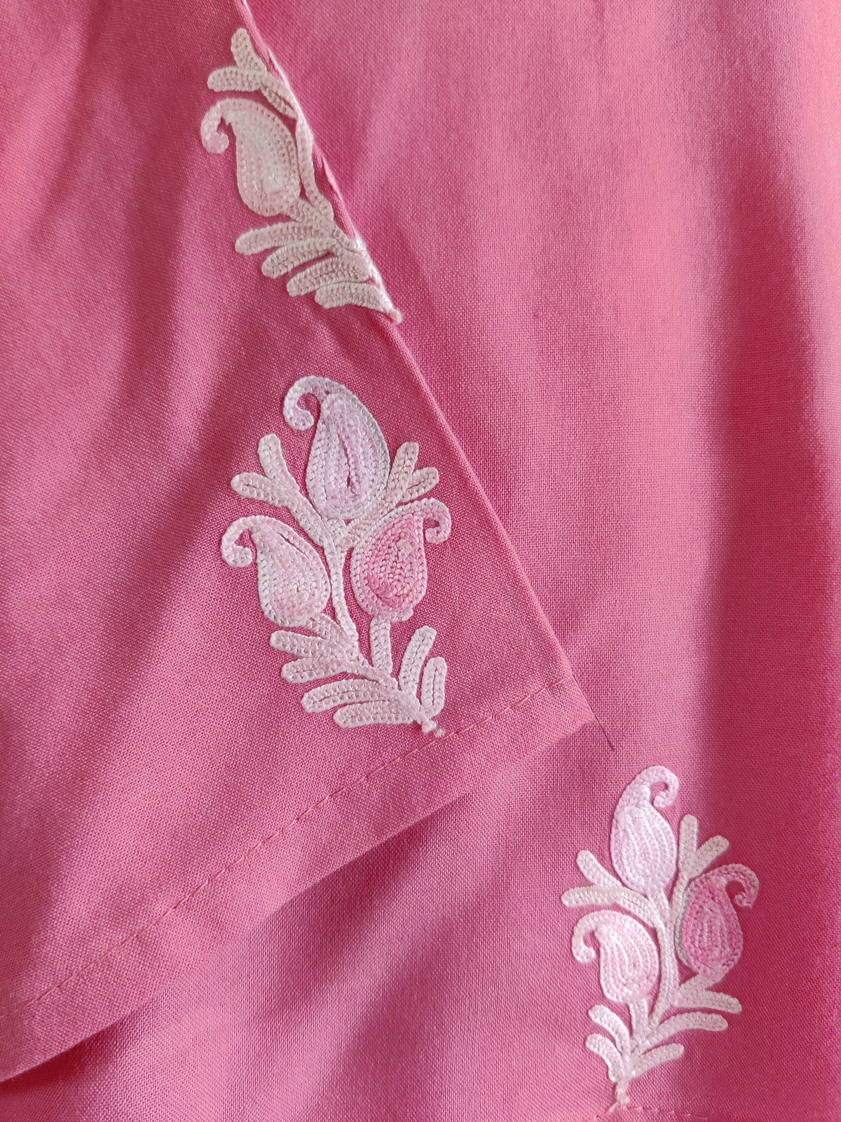 Close-up of small white floral sprigs on the pink kurti’s sleeve and body.