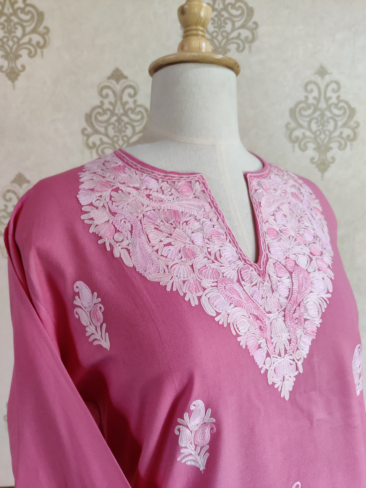 Angled neckline detail of the pink kurti, showing dense white flowers around the long slit opening.