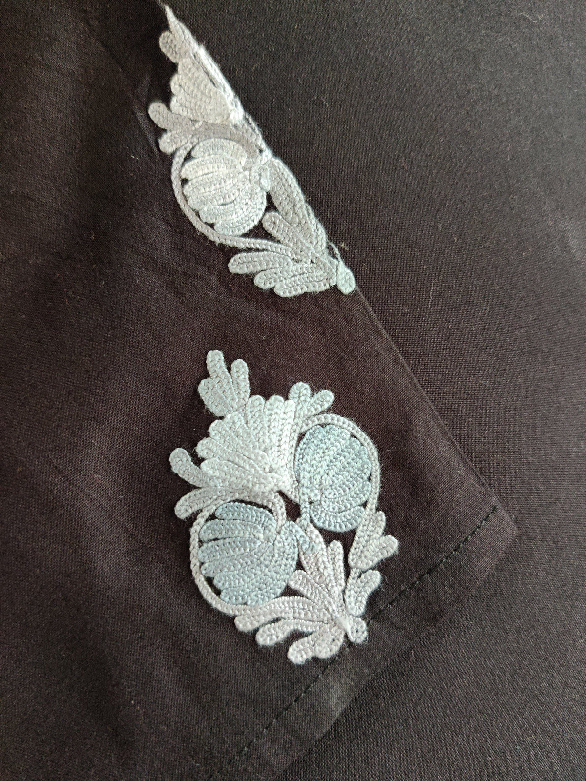 Close-up of the black sleeve with small silver-grey Aari floral motifs above the plain cuff.