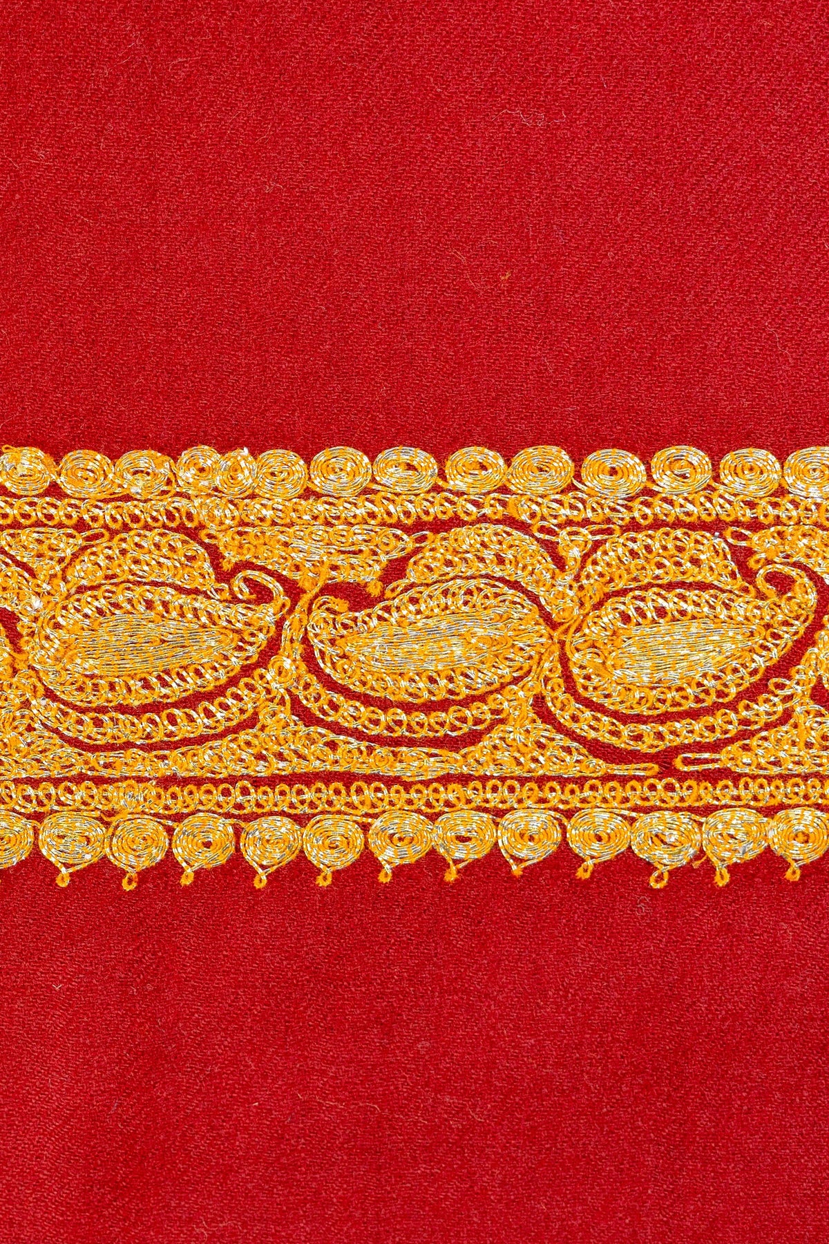 Close-up of the narrow golden Tilla border on the red Merino wool shawl, showing repeating small paisley motifs