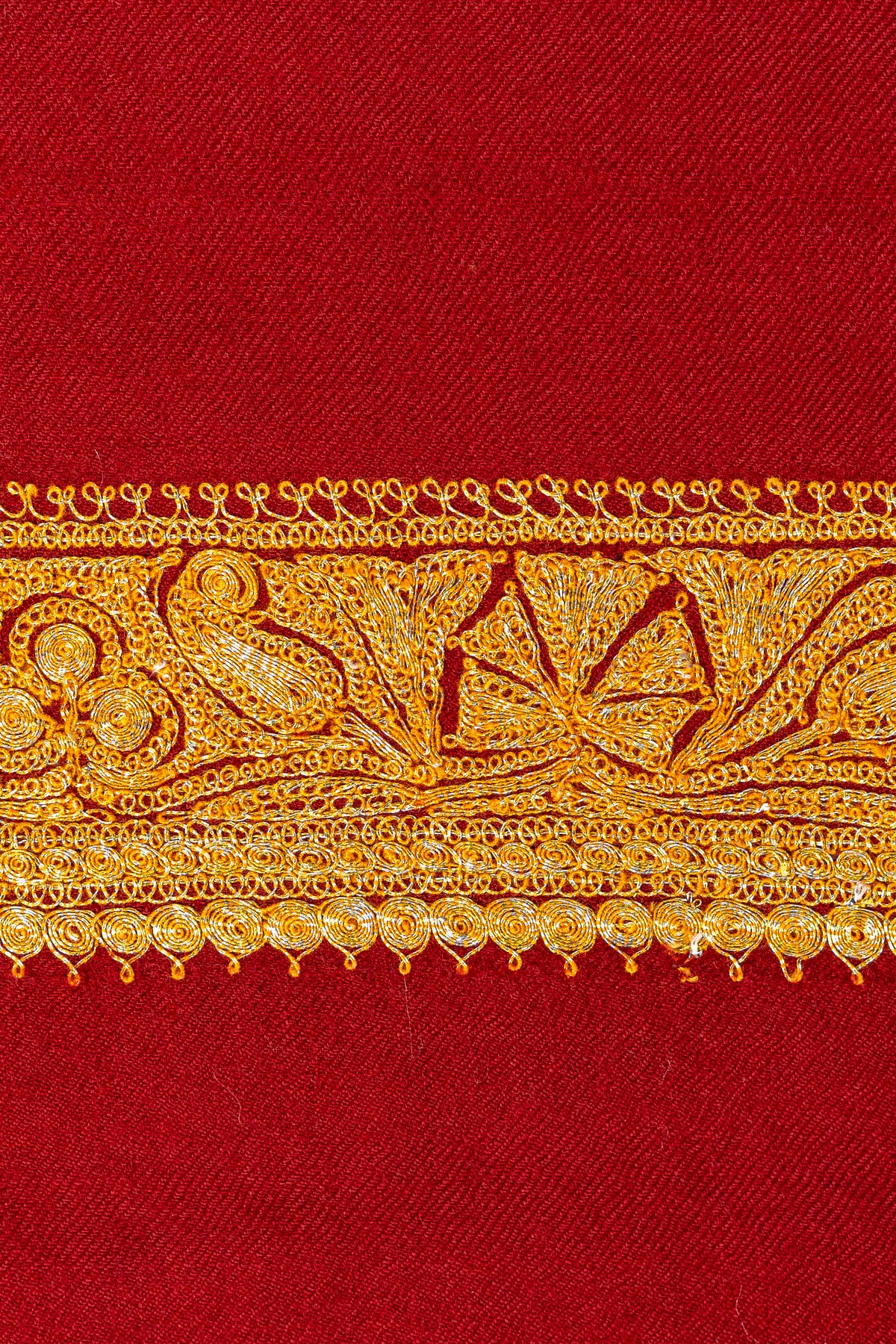 Macro detail of the red shawl’s gold Tilla border, with curling stems, flowers and small looped accents.