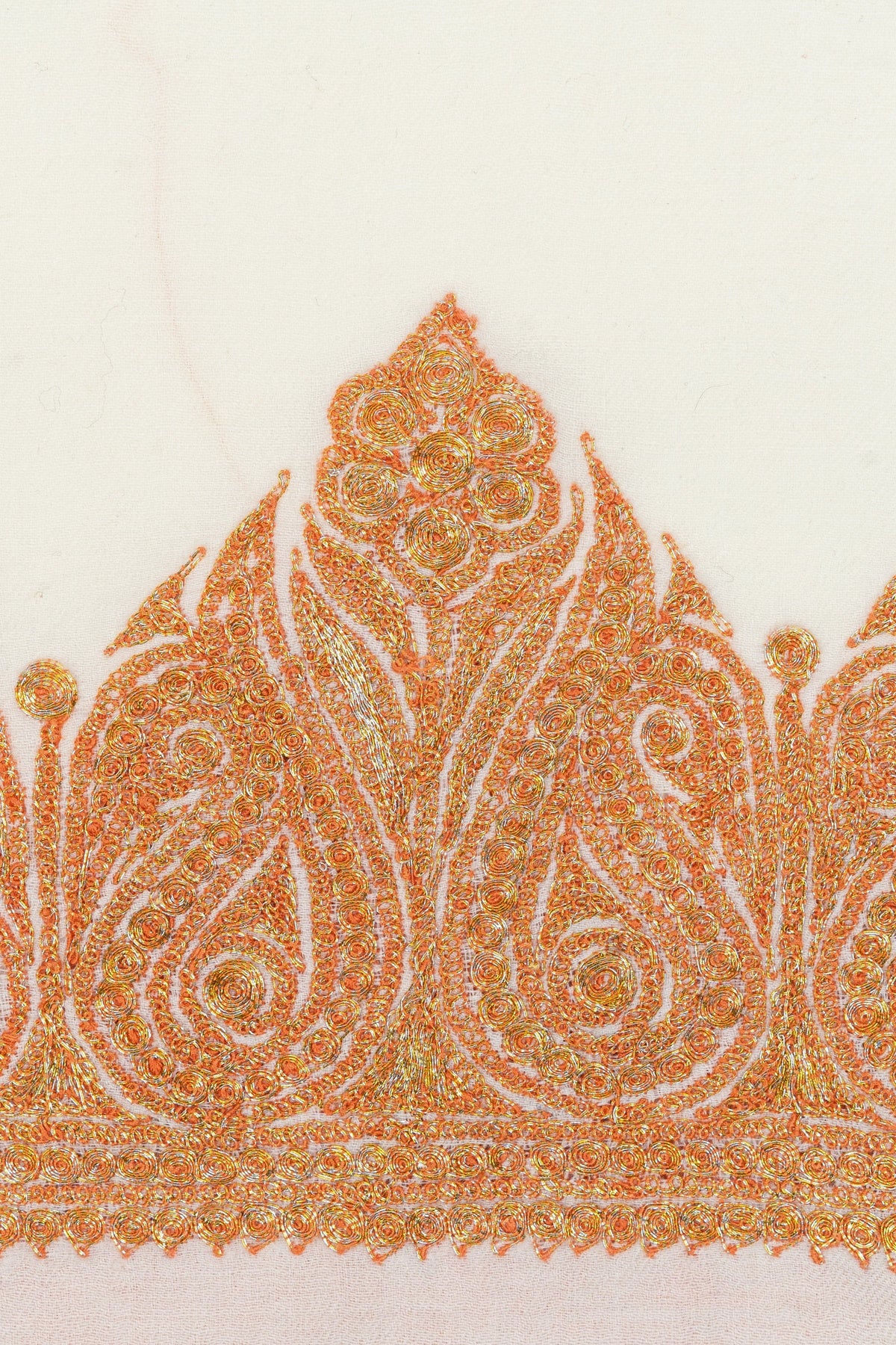 Close-up of the orange-gold paisley Tilla border on a white Merino wool shawl