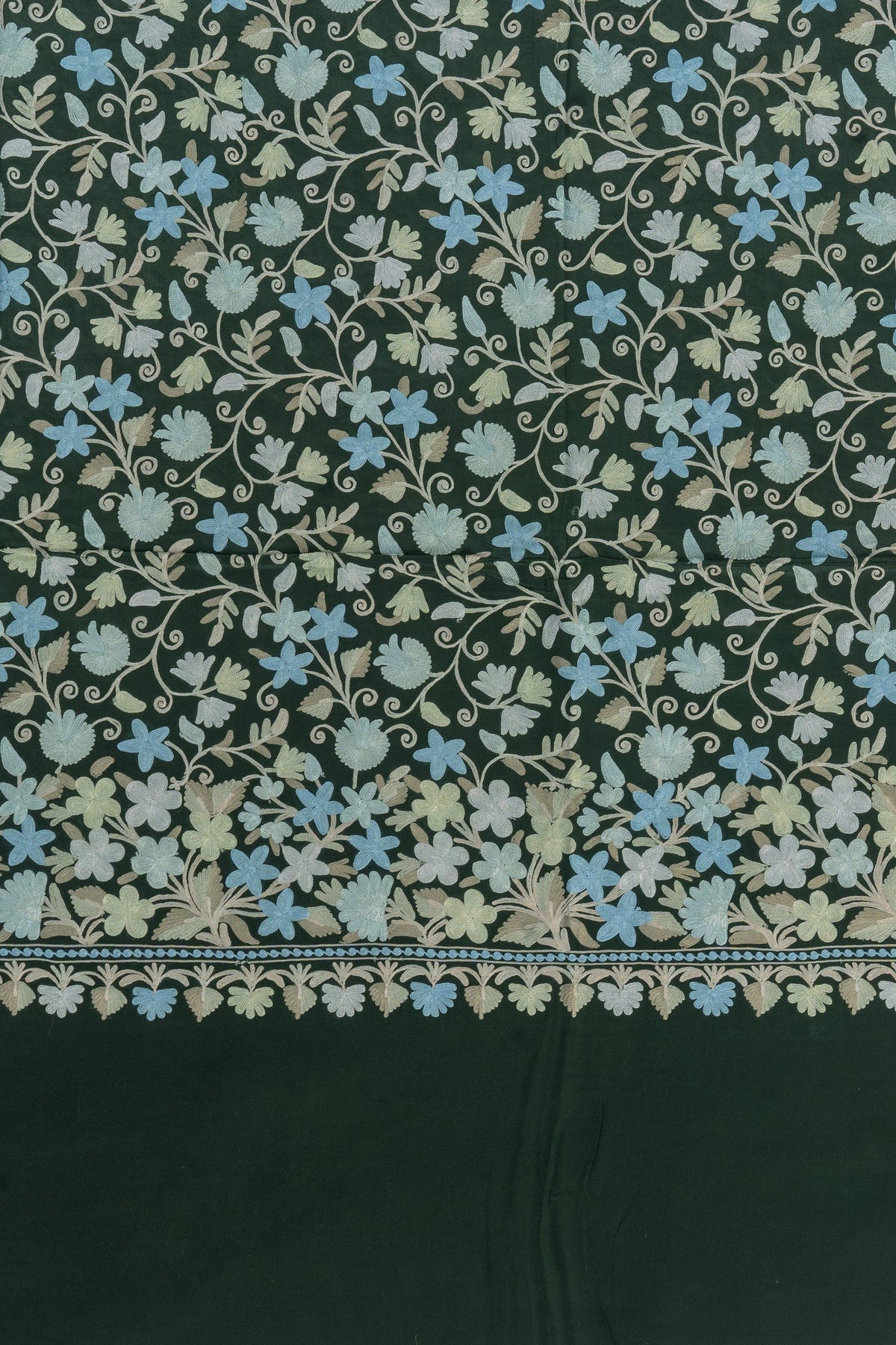 Flat pallu detail of a green crepe saree with cream and pale blue Aari floral vines above a narrow leaf-edged border